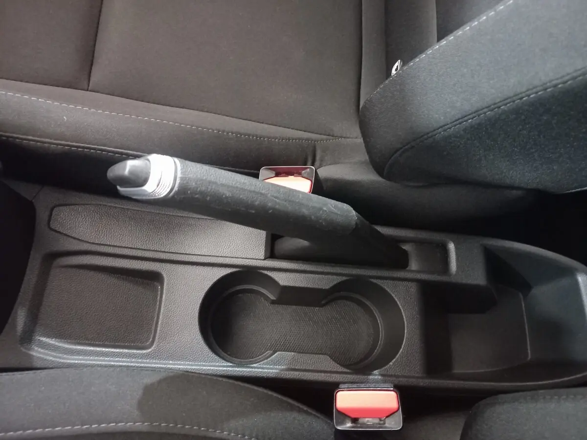 Vue rapprochée de la console centrale noire avec frein à main et porte-gobelets de la Renault Clio Air Nav Blue dCi 85 blanche.