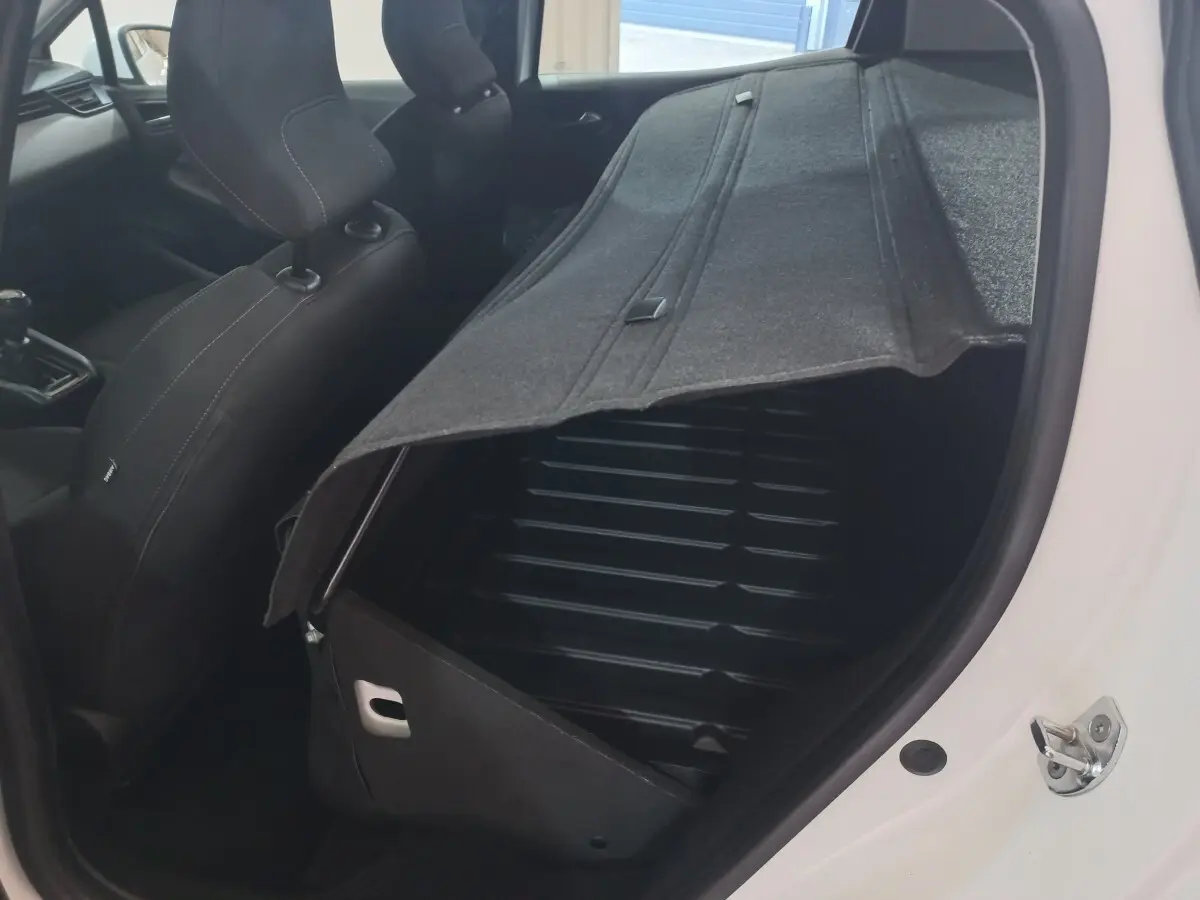 Vue intérieure côté droit de la Renault Clio blanche 2020 avec banquette arrière rabattue et coffre ouvert.