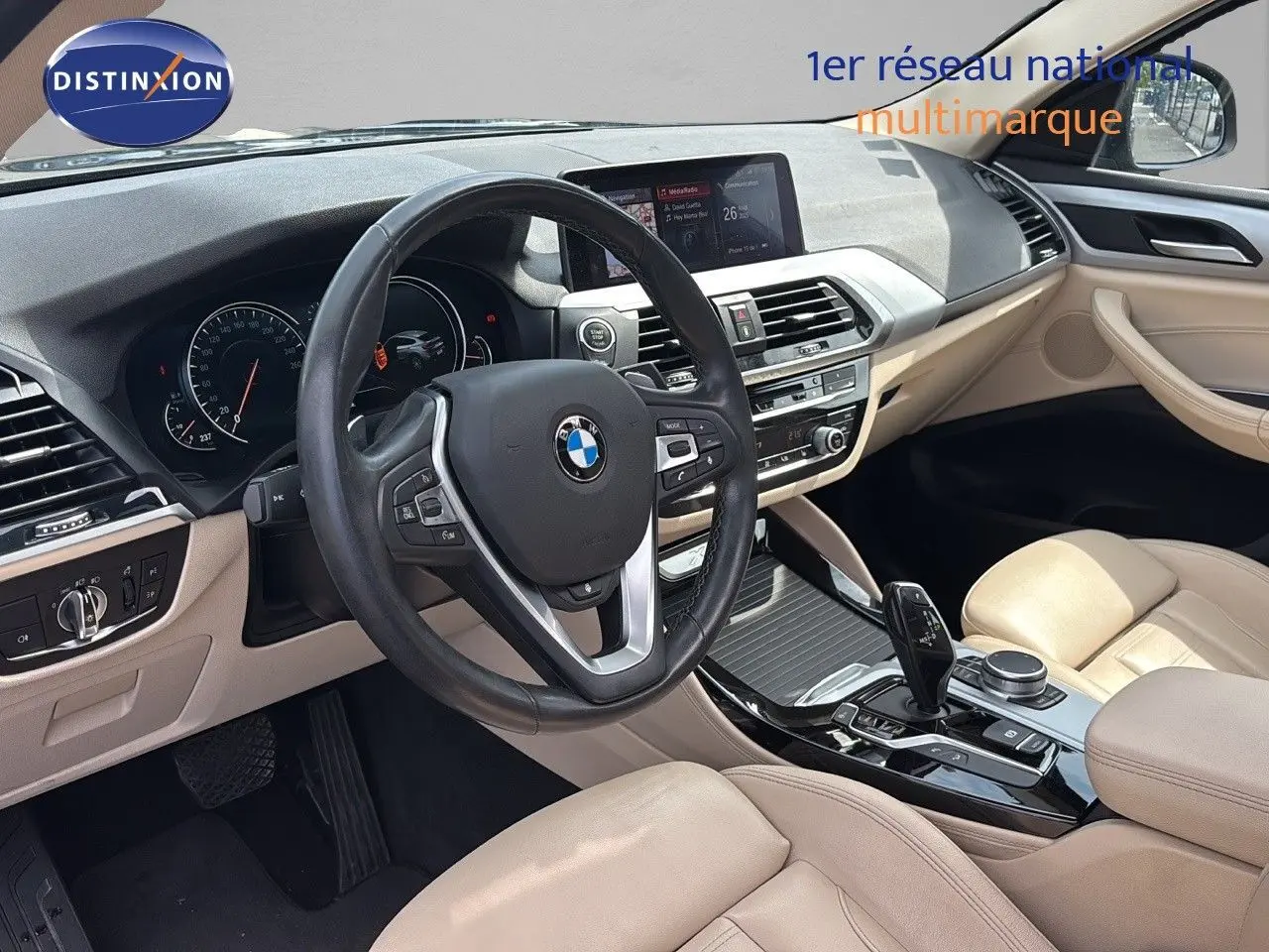 Intérieur beige clair de BMW X4 XDRIVE 30D 2019, vue du poste de conduite avec volant multifonction et console centrale moderne.