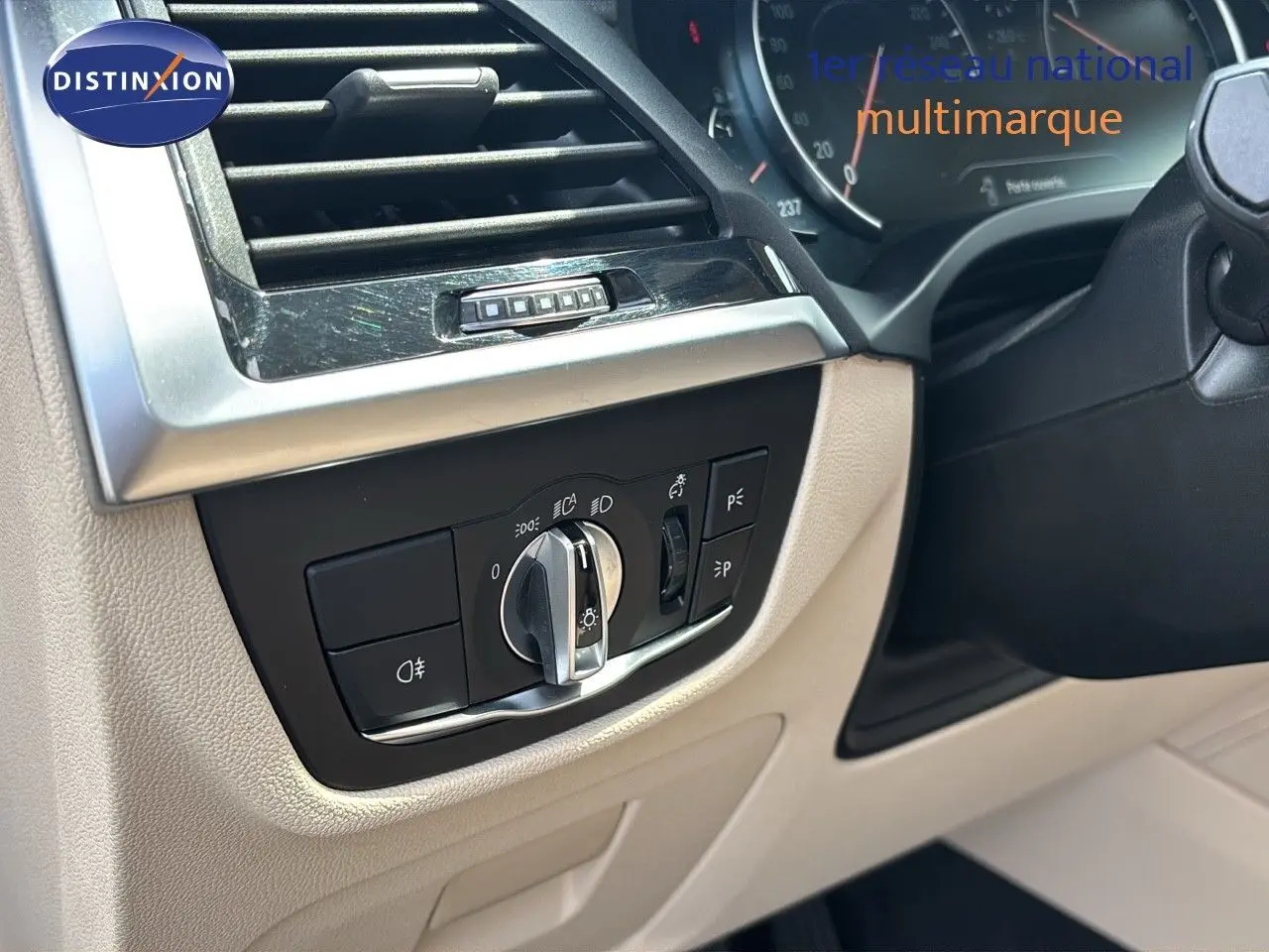 Détail du tableau de bord beige d'une BMW X4 XDRIVE 30D 2019 avec commandes d'éclairage et aérateur.