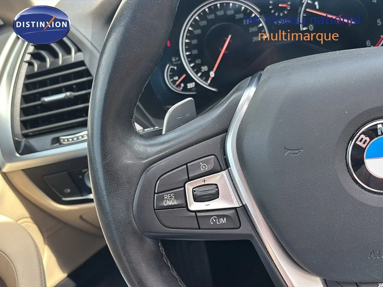 Gros plan sur le volant noir et les commandes de régulateur de vitesse du BMW X4 XDRIVE 30D intérieur beige.