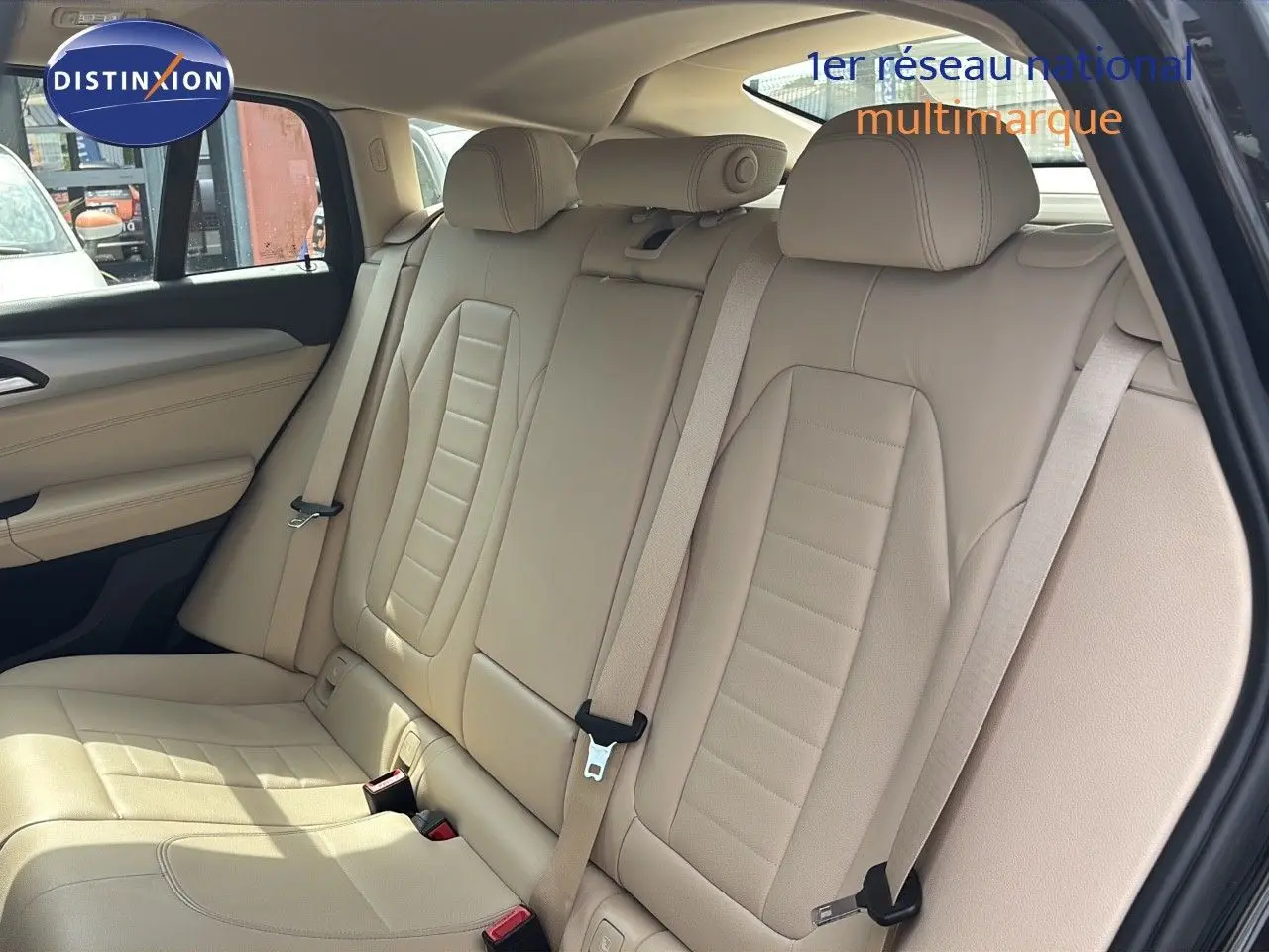 Vue intérieure arrière du BMW X4 XDRIVE 30D 2019 avec sièges en cuir beige lumineux et ceintures de sécurité visibles.