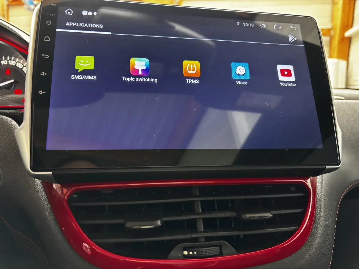 Écran tactile 7 pouces du système multimédia de la Peugeot 208 rouge, avec commandes d'aération en dessous.