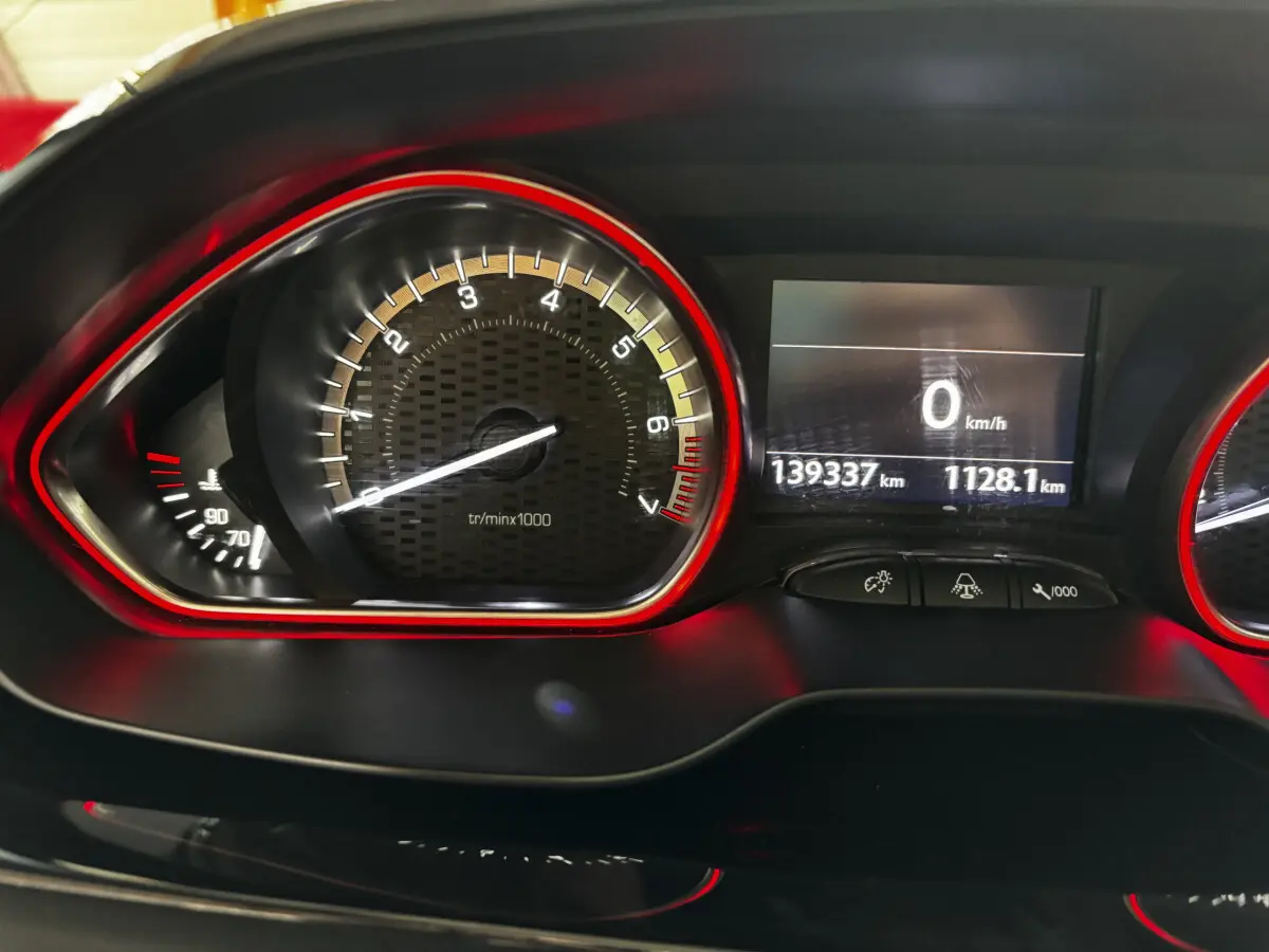 Gros plan sur le tableau de bord de la Peugeot 208 GTI 2013 avec compte-tours et affichage digital rouge et noir.