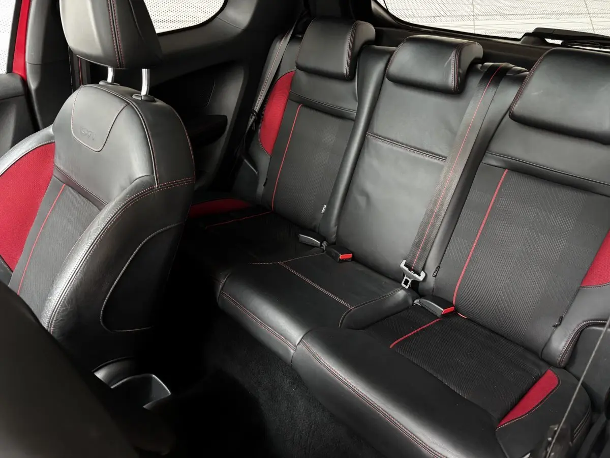 Vue intérieure arrière de la Peugeot 208 GTI 2013, sièges en cuir noir avec surpiqûres rouges et inserts rouges.