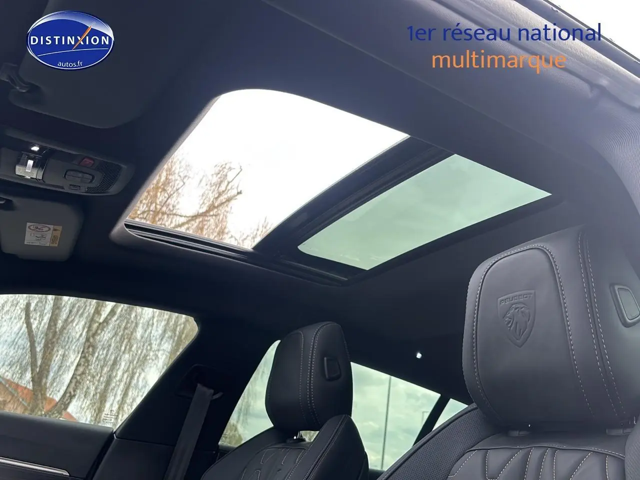 Vue intérieure du toit ouvrant panoramique et des sièges avant en cuir noir du Peugeot 508 SW Hybrid 225 gris titane 2024.