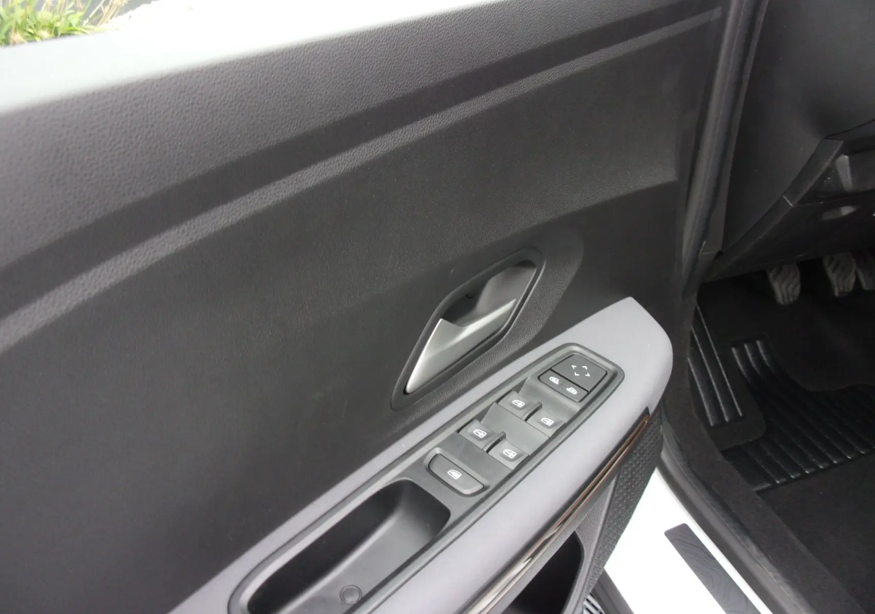 Vue rapprochée de la porte avant gauche du Dacia Jogger blanc 2025, avec commandes électriques des vitres et poignée argentée.