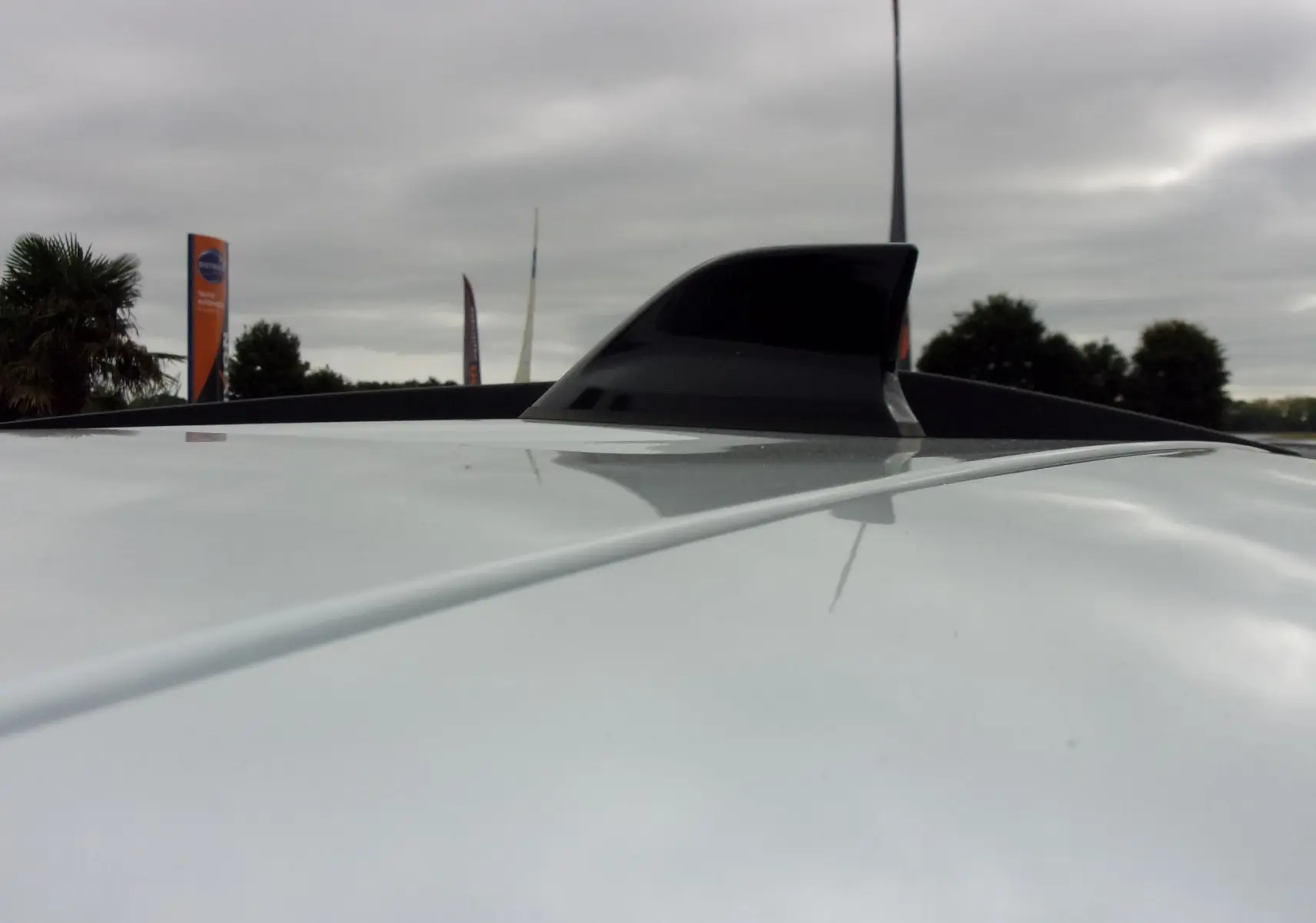 Gros plan sur l'antenne requin noire sur le toit blanc d'un Dacia Jogger 2025 sous ciel nuageux.