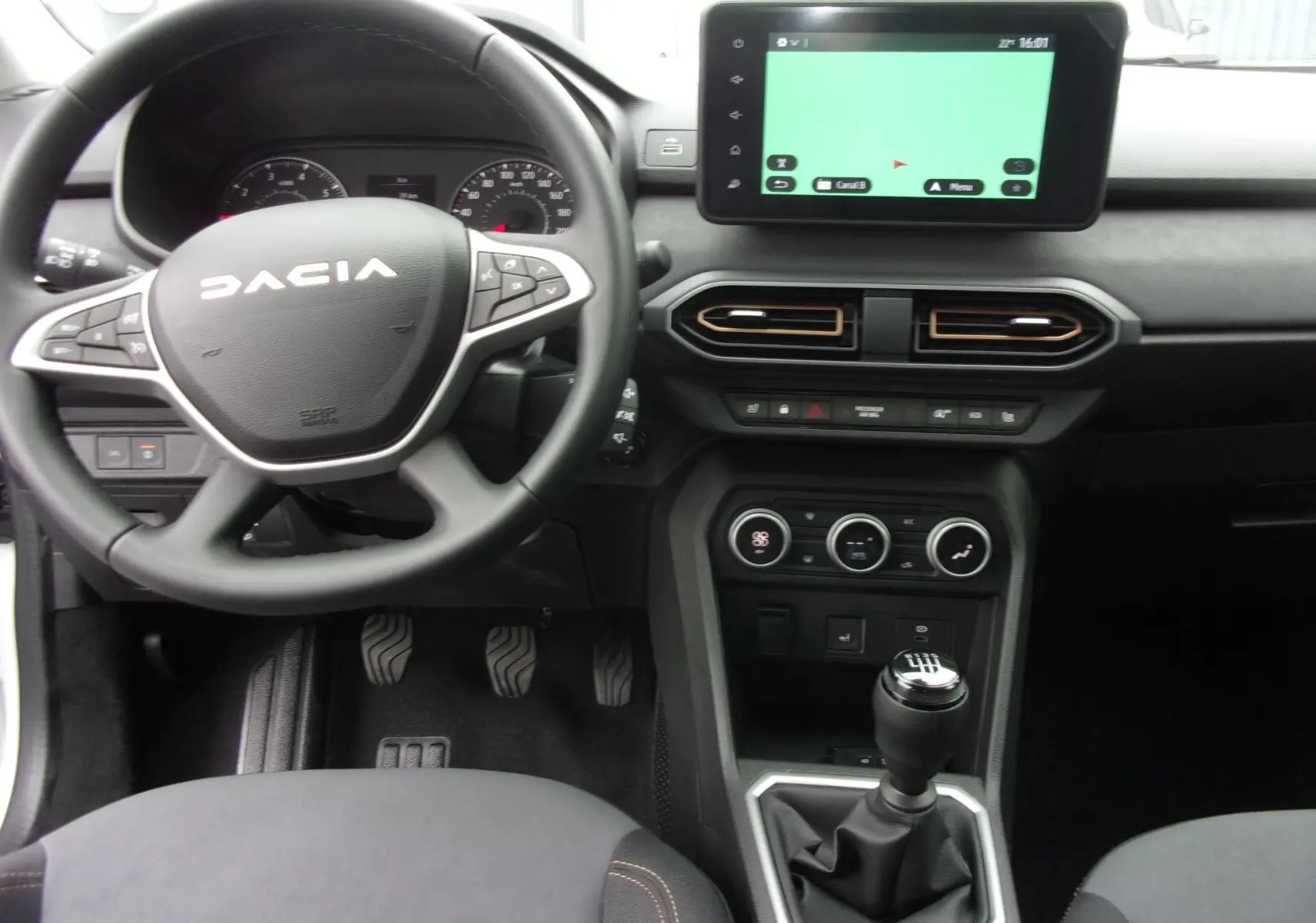 Vue intérieure avant du Dacia Jogger blanc 2025, mettant en valeur le volant multifonction, la boîte manuelle et l'écran tactile central.