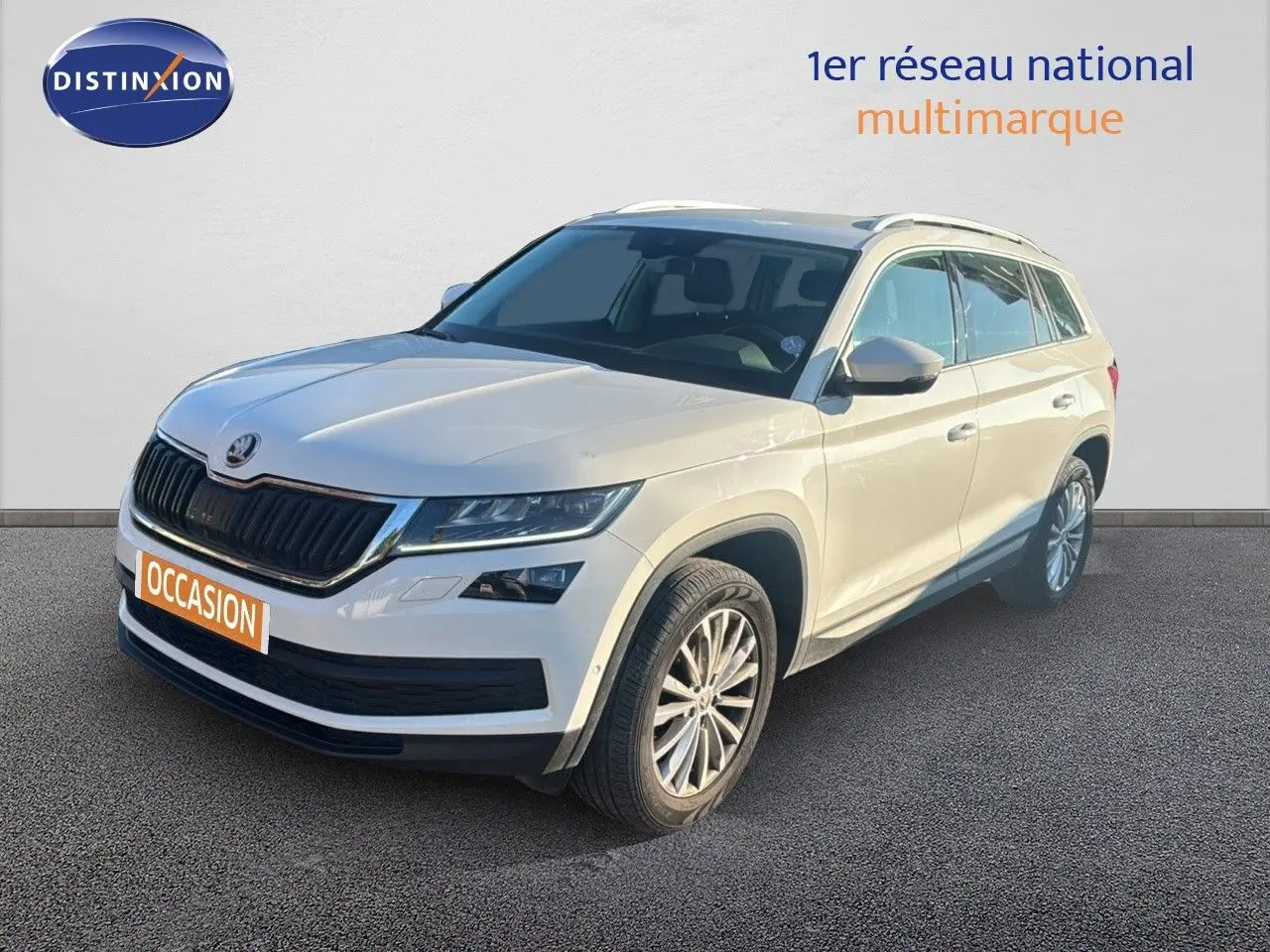 SUV Skoda Kodiaq blanc en 3/4 avant droit, avec calandre noire et jantes alliage visibles sur fond neutre.