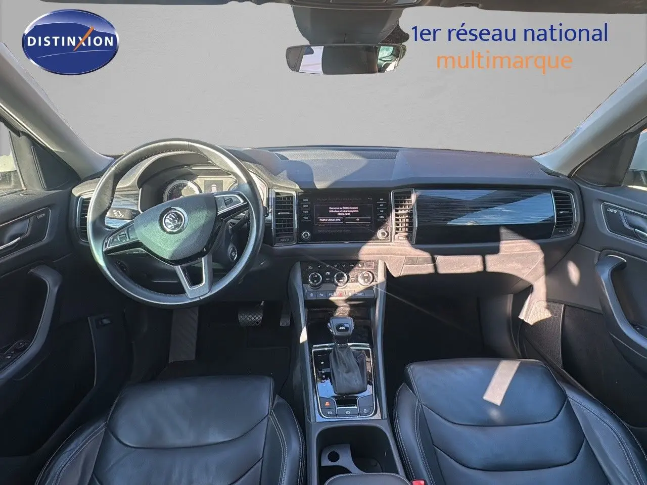 Intérieur du Skoda Kodiaq blanc 2018, vue frontale du poste de conduite avec volant cuir noir et console centrale.