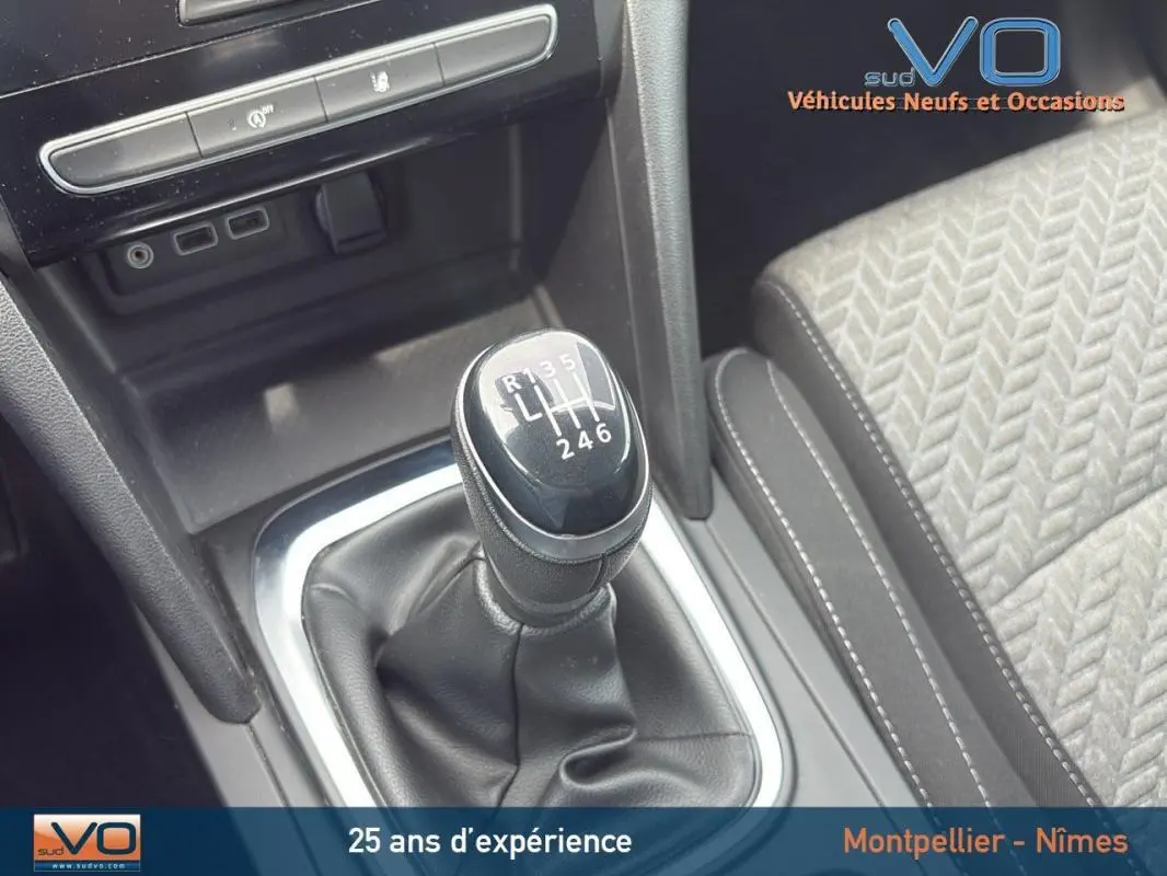 Le levier de vitesses manuel noir de la Renault Mégane IV gris foncé, avec partie centrale et siège tissu à motifs visibles.