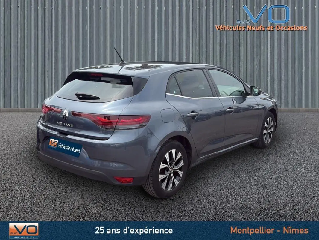 Renault Mégane IV Berline gris foncé vue 3/4 arrière droit, jantes alliage 16 pouces et feux arrière LED allumés.