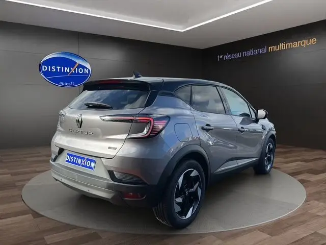 Vue 3/4 arrière droite du Renault Captur 2025 gris Cassiopée avec toit noir et roues distinctives en concession.
