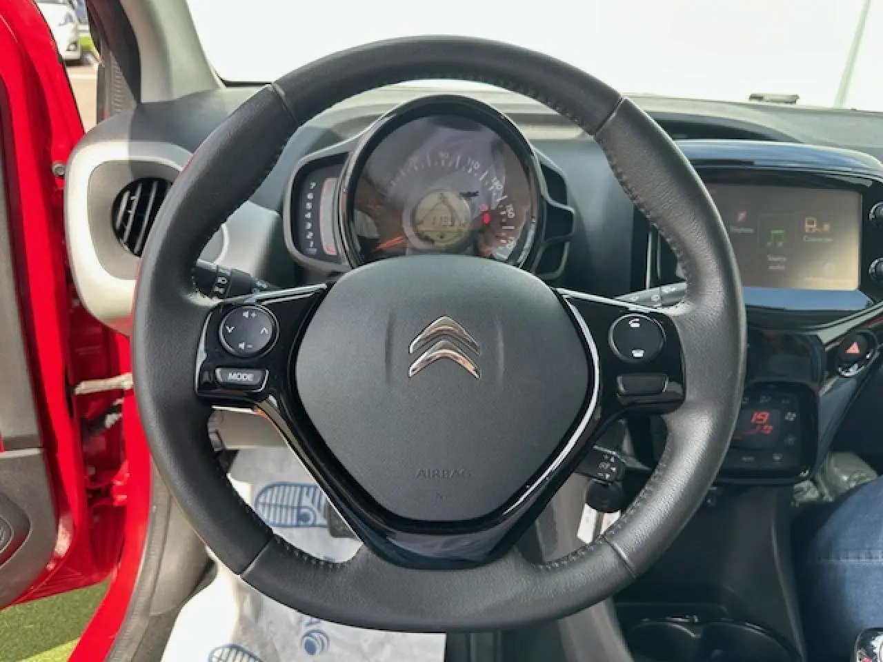 Volant en croûte de cuir de la Citroën C1 rouge Scarlet, vue centrée sur le tableau de bord et l'écran tactile.