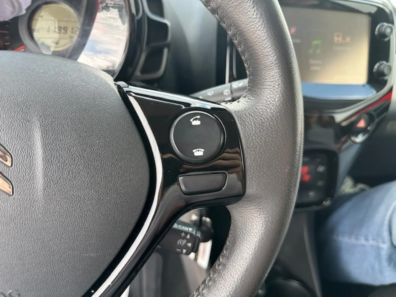 Gros plan sur le volant en croûte de cuir de la Citroën C1 rouge Scarlet avec commandes Bluetooth visibles.