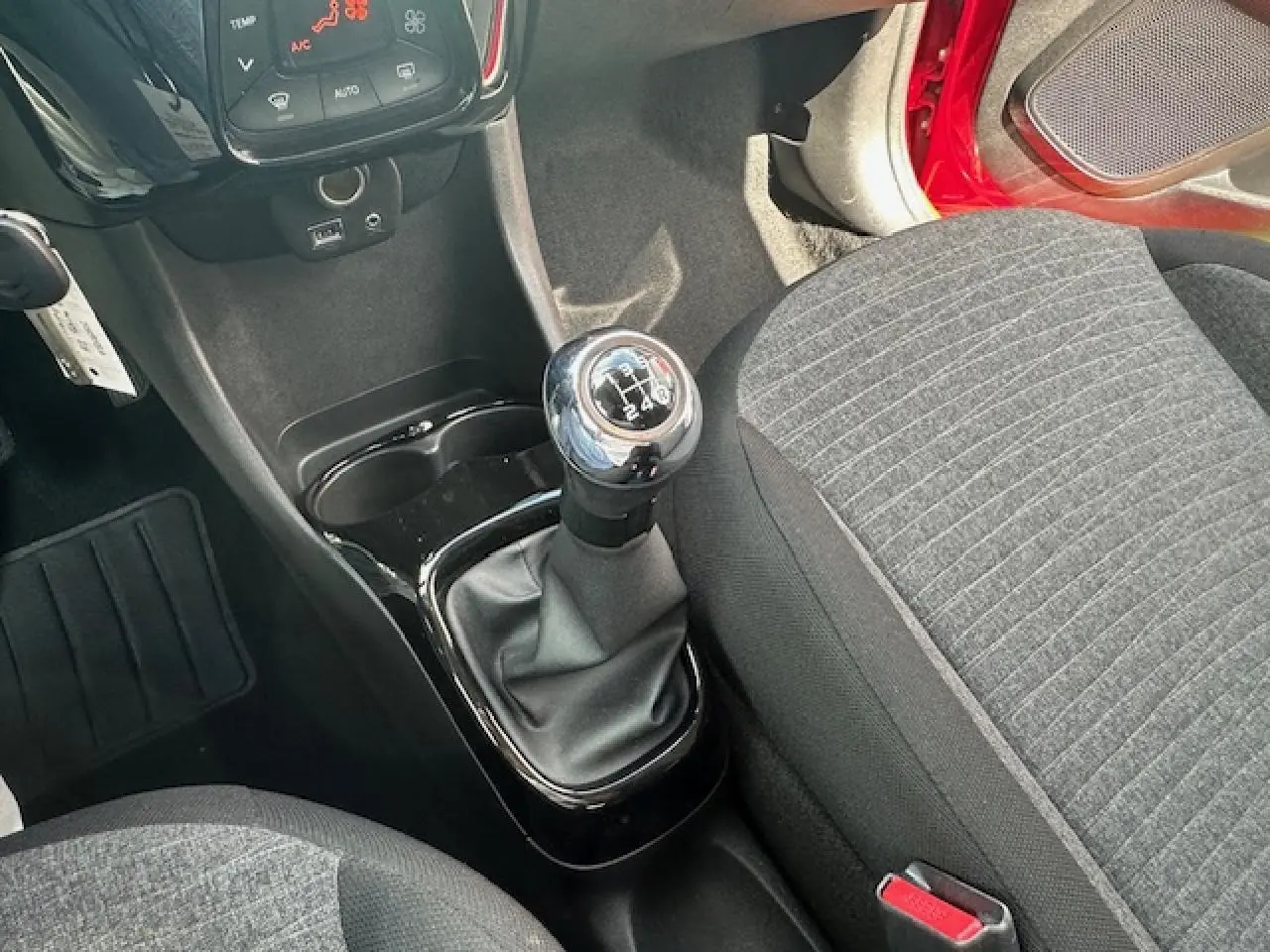 Vue intérieure centrée sur le levier de vitesses manuel et siège tissu gris de la Citroën C1 rouge scarlet 2014