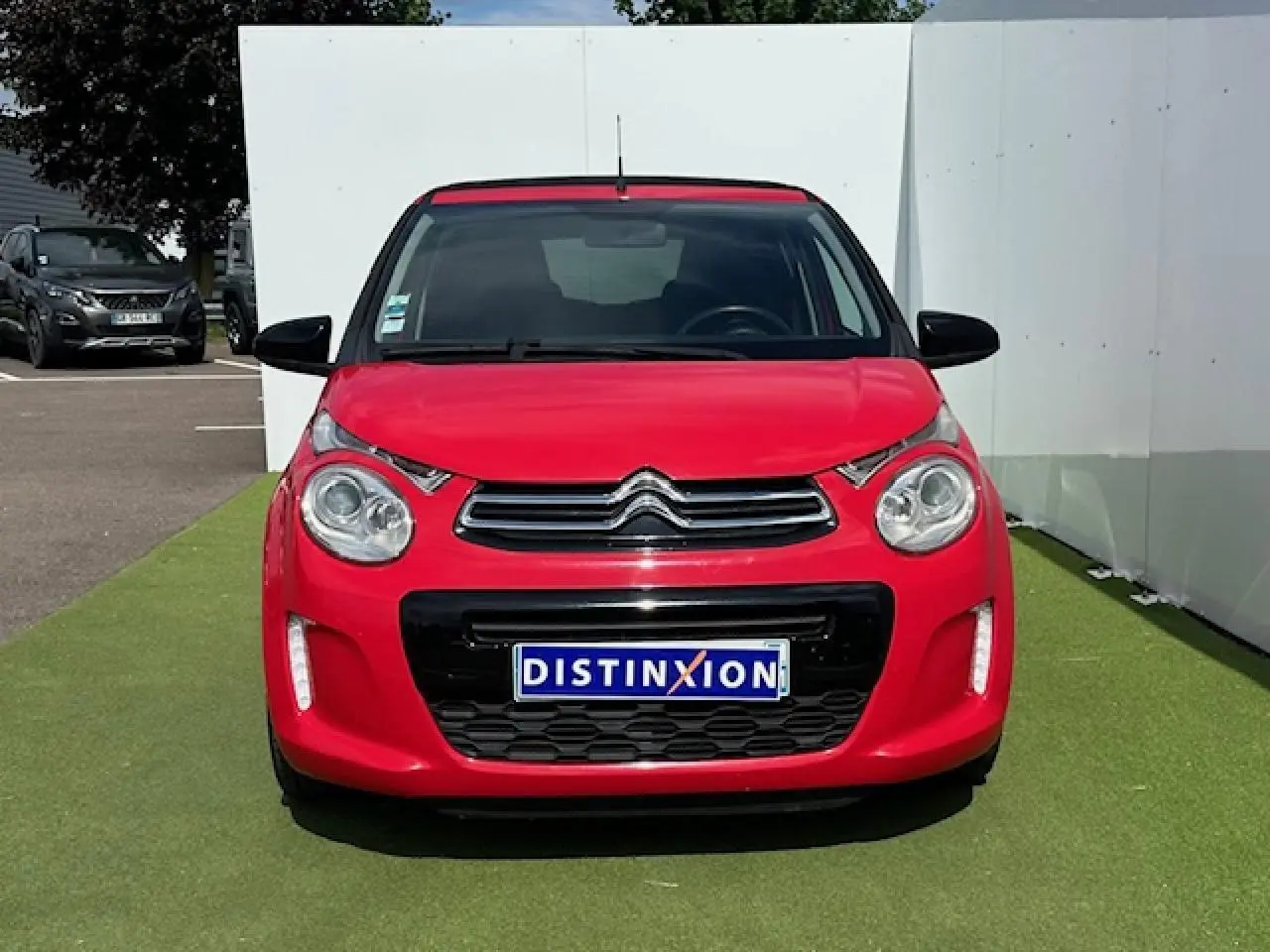 Vue frontale d'une Citroën C1 rouge Scarlet avec calandre chromée et feux diurnes à LED verticaux.