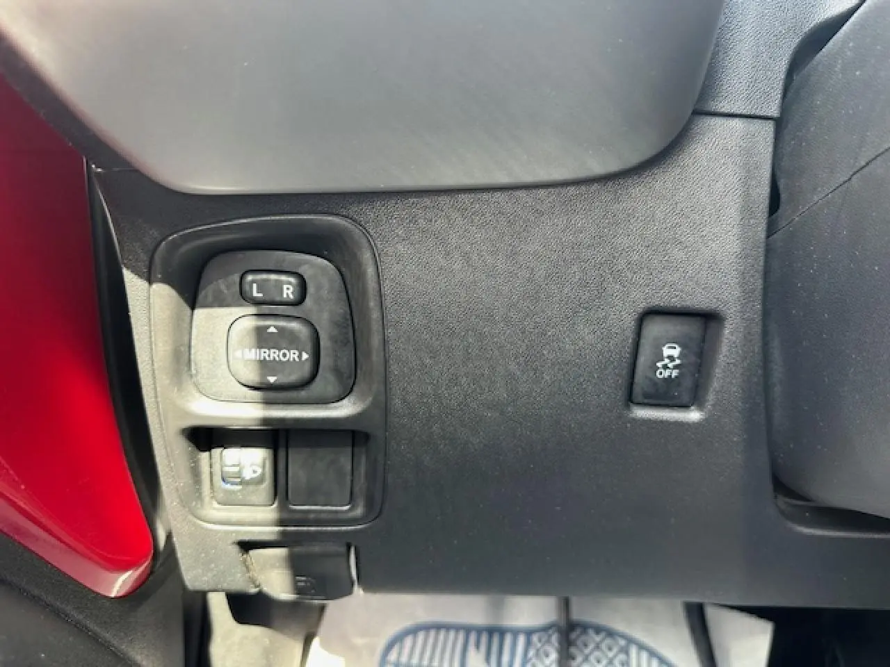 Panneau de commandes côté gauche avec réglage des rétroviseurs et bouton ESP sur une Citroën C1 rouge Scarlet 2014.
