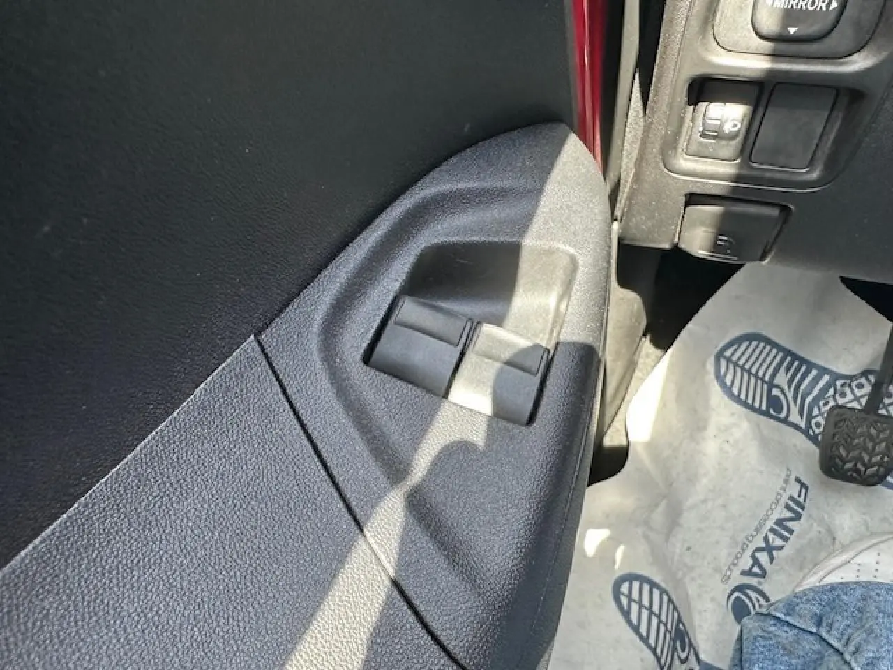 Détail des commandes de lève-vitres côté gauche dans une Citroën C1 rouge Scarlet de 2014.