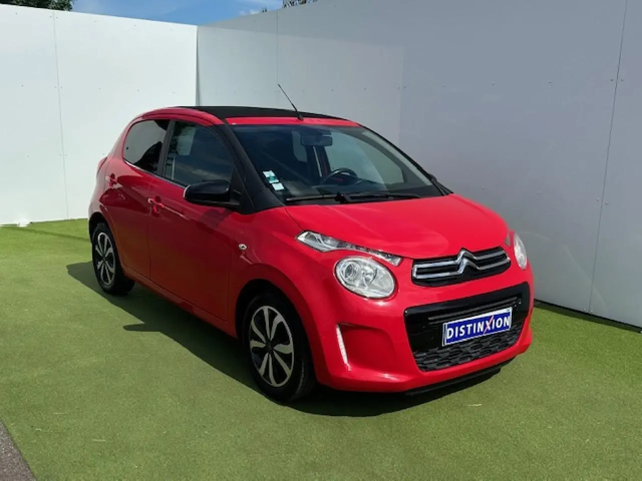 Citroën C1 rouge Scarlet vue 3/4 avant droit avec toit ouvrant et jantes alliage noires et argentées.