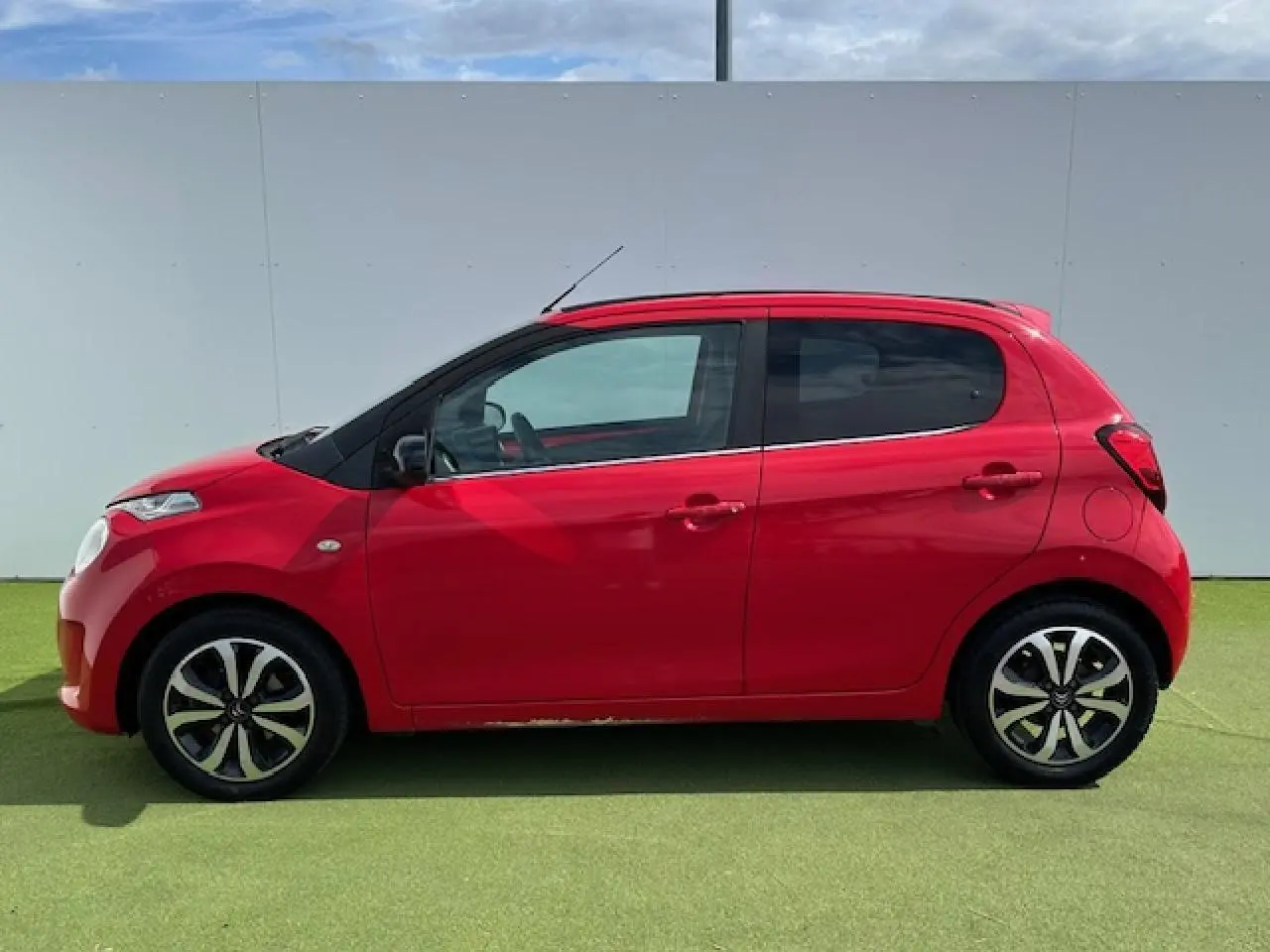 Profil droit d'une Citroën C1 rouge Scarlet de 2014 avec jantes alliage 15 pouces et coques de rétroviseurs noires.