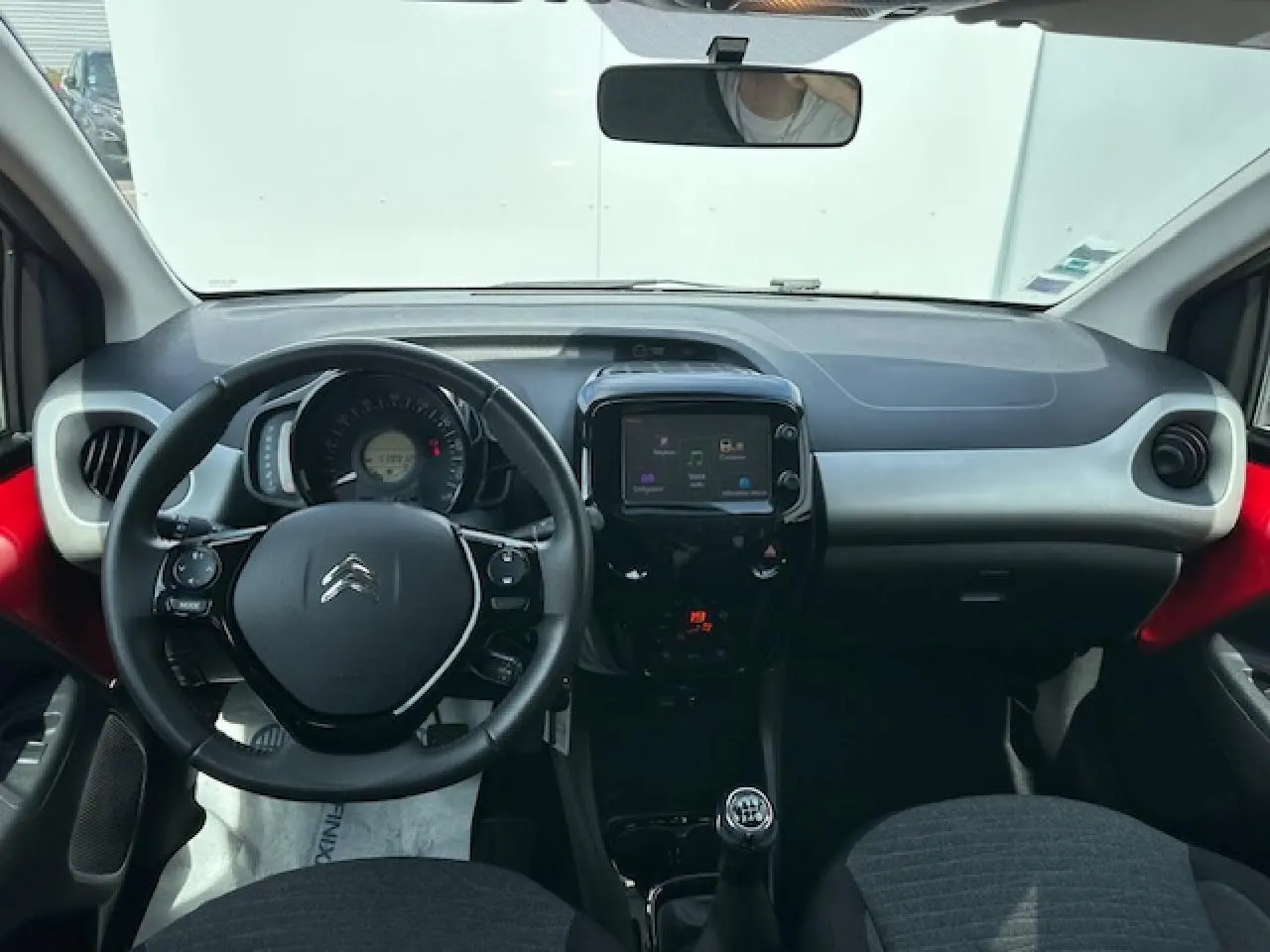 Intérieur avant de la Citroën C1 rouge Scarlet 2014, tableau de bord avec volant cuir et écran tactile central.