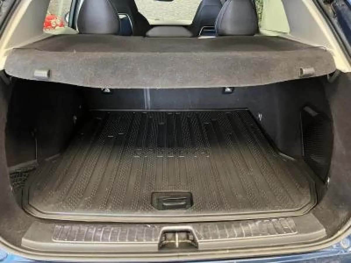 Coffre ouvert du LYNK & CO 01 bleu, vue arrière montrant la protection de coffre et la banquette arrière noire.
