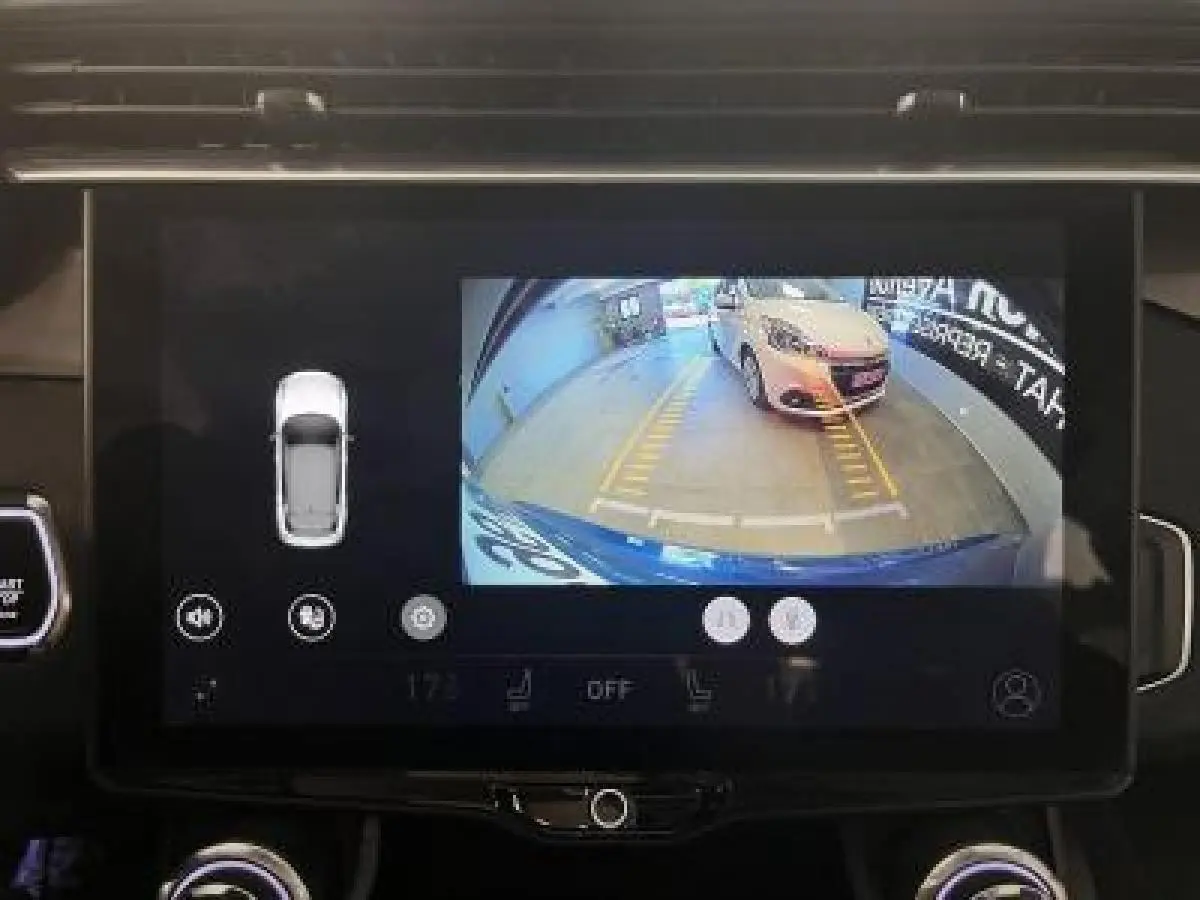 Écran tactile montrant la caméra de recul du LYNK & CO 01 bleu avec guidage de stationnement en garage.