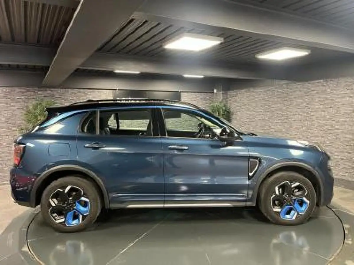 Profil côté gauche du SUV Lynk & Co 01 bleu métallisé avec jantes 20 pouces bicolores en intérieur lumineux.