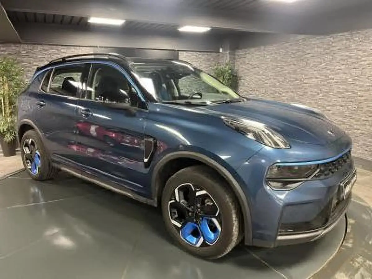 Vue 3/4 avant droite du SUV Lynk & Co 01 bleu métallisé avec jantes alliage noires et bleues dans un showroom.