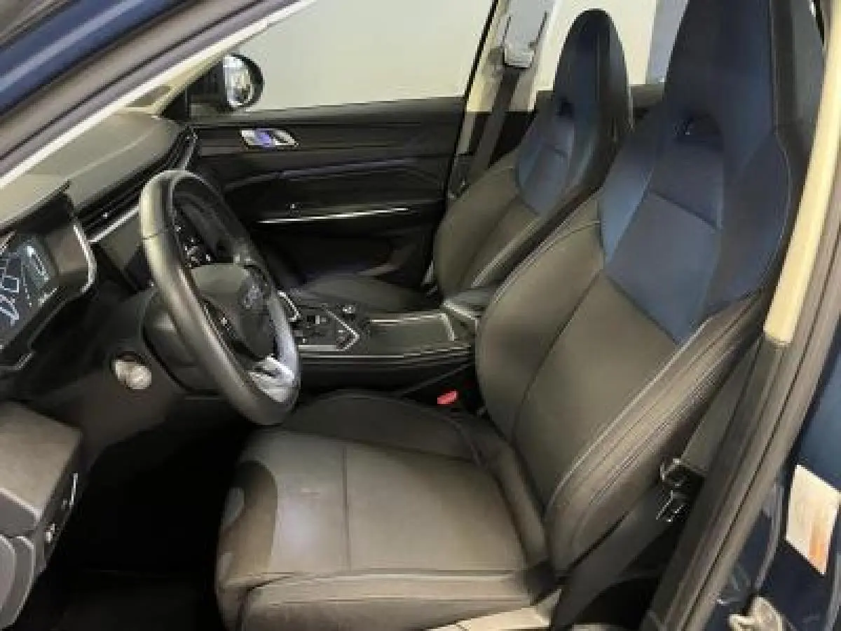 Intérieur avant droit du LYNK & CO 01 bleu, sièges tissu noir et tableau de bord moderne avec écran digital.