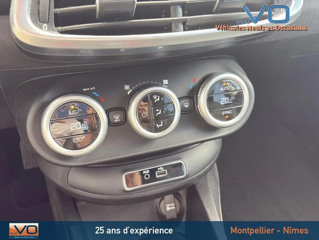 Gros plan sur la console centrale de la Fiat 500X gris anthracite, montrant les commandes de climatisation automatique et les ports USB et AUX.