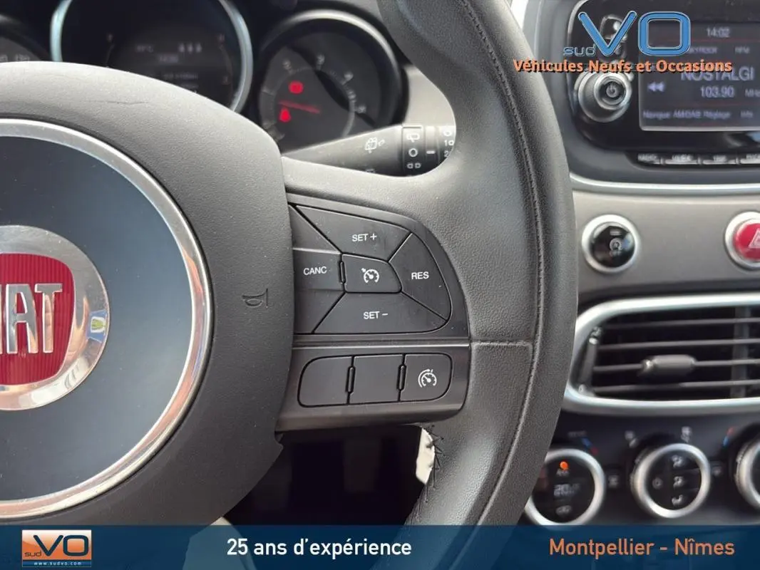 Gros plan sur le volant cuir et le tableau de bord du Fiat 500X gris anthracite avec commandes de régulateur de vitesse visibles.