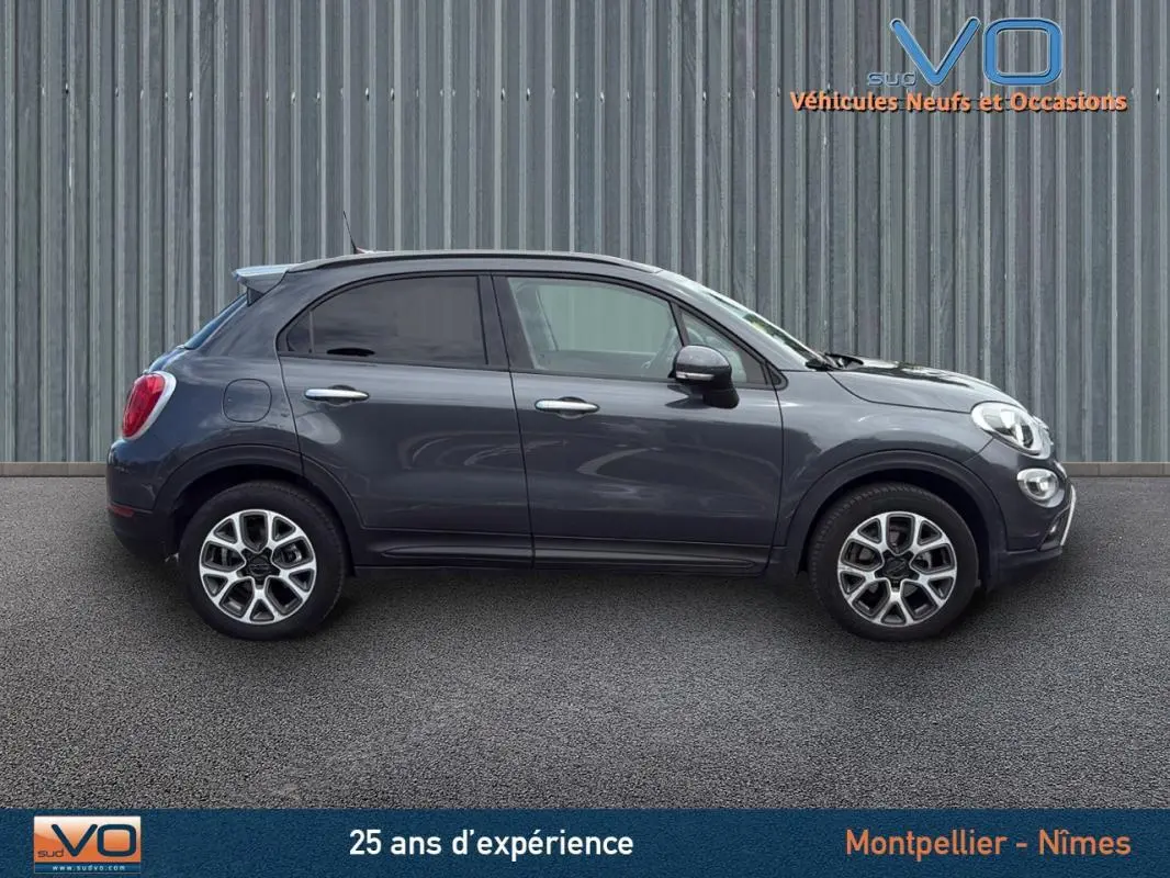 Profil côté gauche d'un FIAT 500X gris anthracite de 2015 avec jantes alliage 17 pouces sur fond urbain.