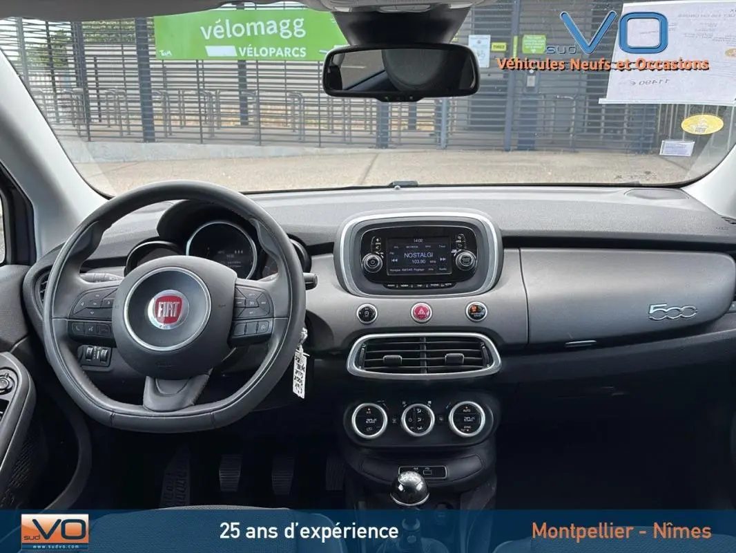 Vue intérieure frontale du tableau de bord et volant cuir de la FIAT 500X gris anthracite avec écran tactile et commandes au volant.
