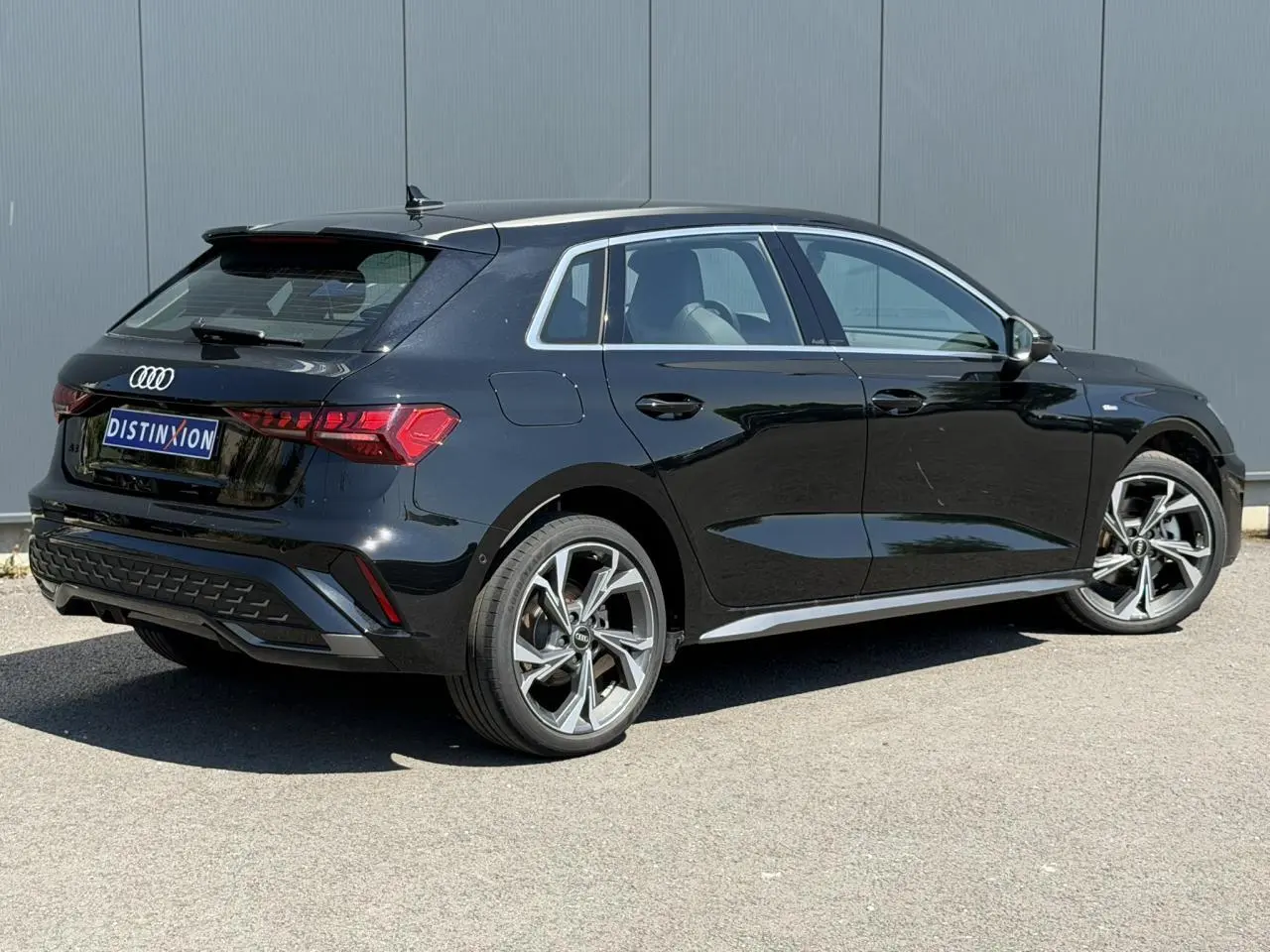 Audi A3 Sportback noir Mythe vue 3/4 arrière droit, jantes alliage 5 branches en Y gris brillant et vitres surteintées.
