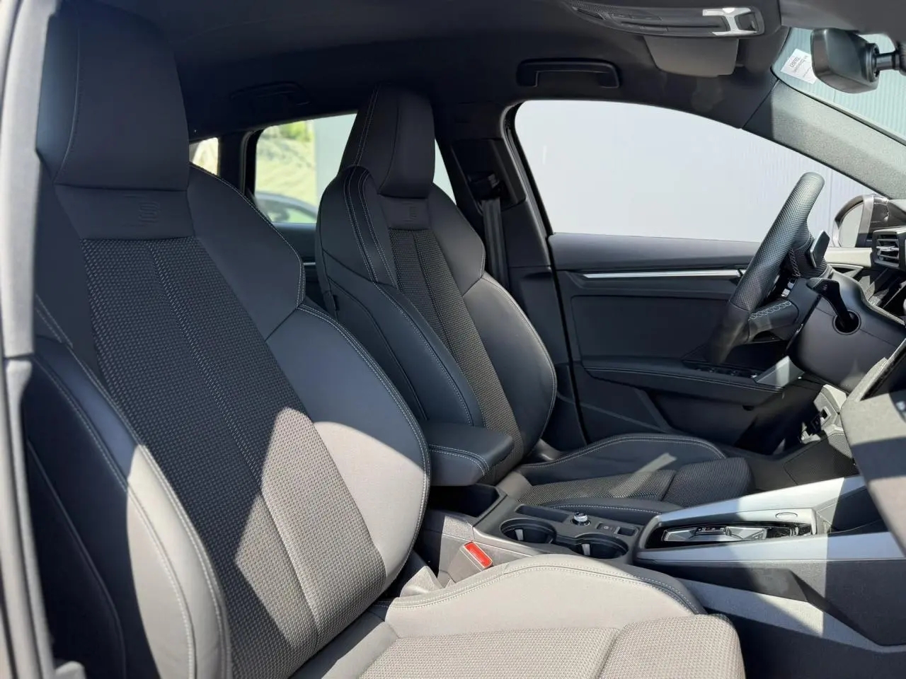 Vue intérieure côté gauche montrant les sièges sport noirs et la console centrale de l'Audi A3 Sportback 2025 S-Line.