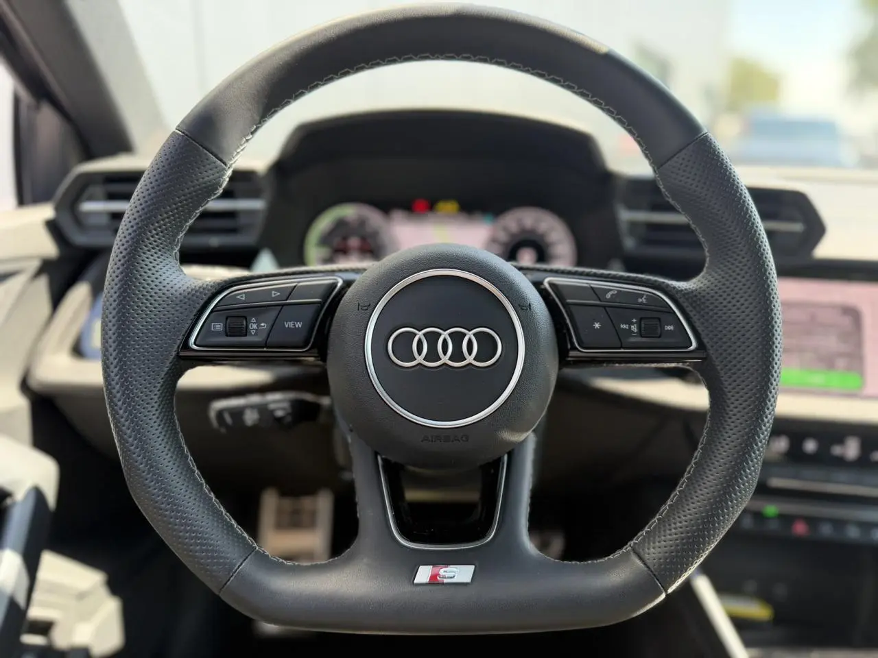 Volant sport en cuir perforé avec logo S Audi, vue frontale centrée sur le tableau de bord intérieur noir.