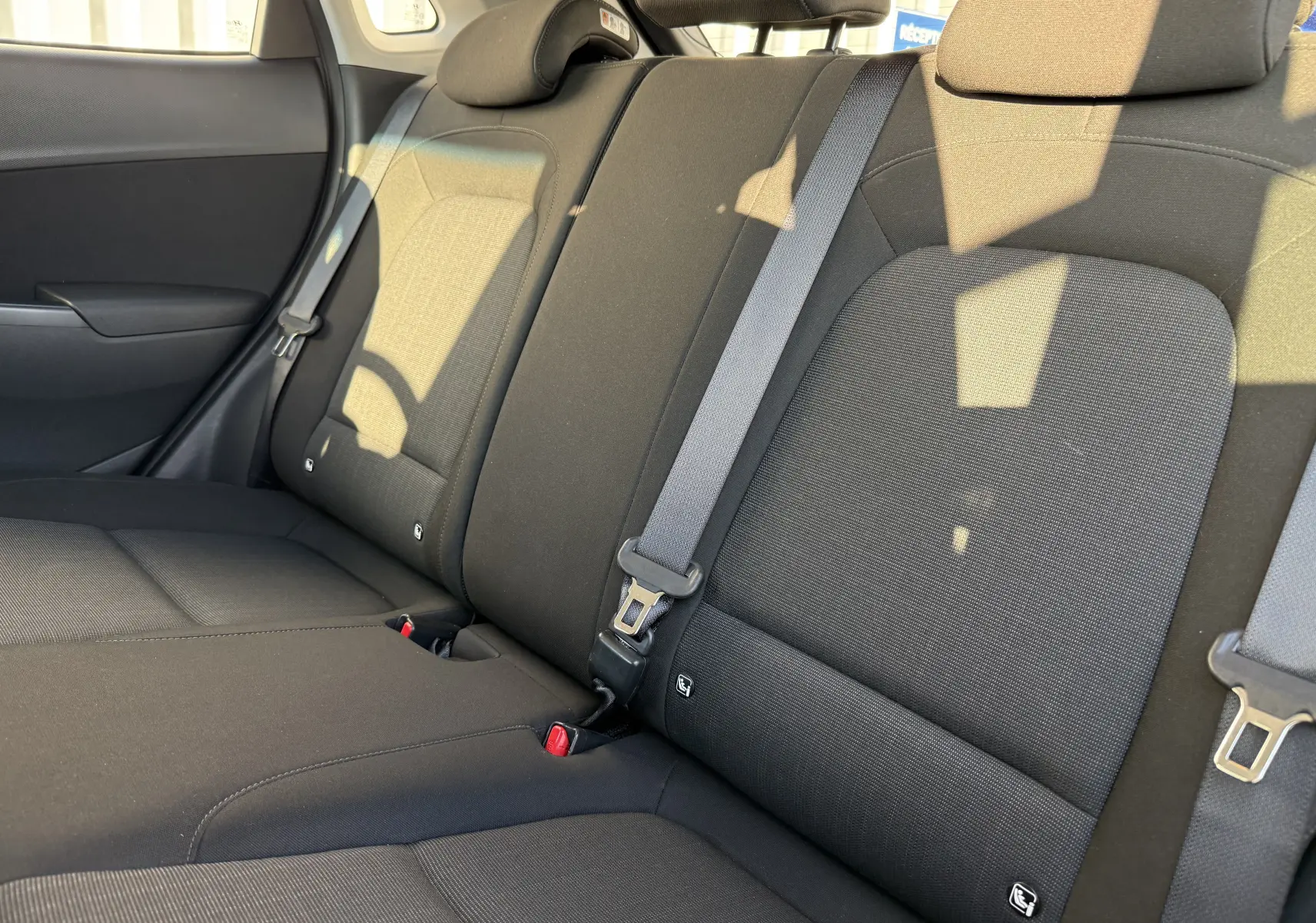 Vue rapprochée des sièges arrière en tissu gris noir du Hyundai Kona 2021 avec ceintures de sécurité visibles.