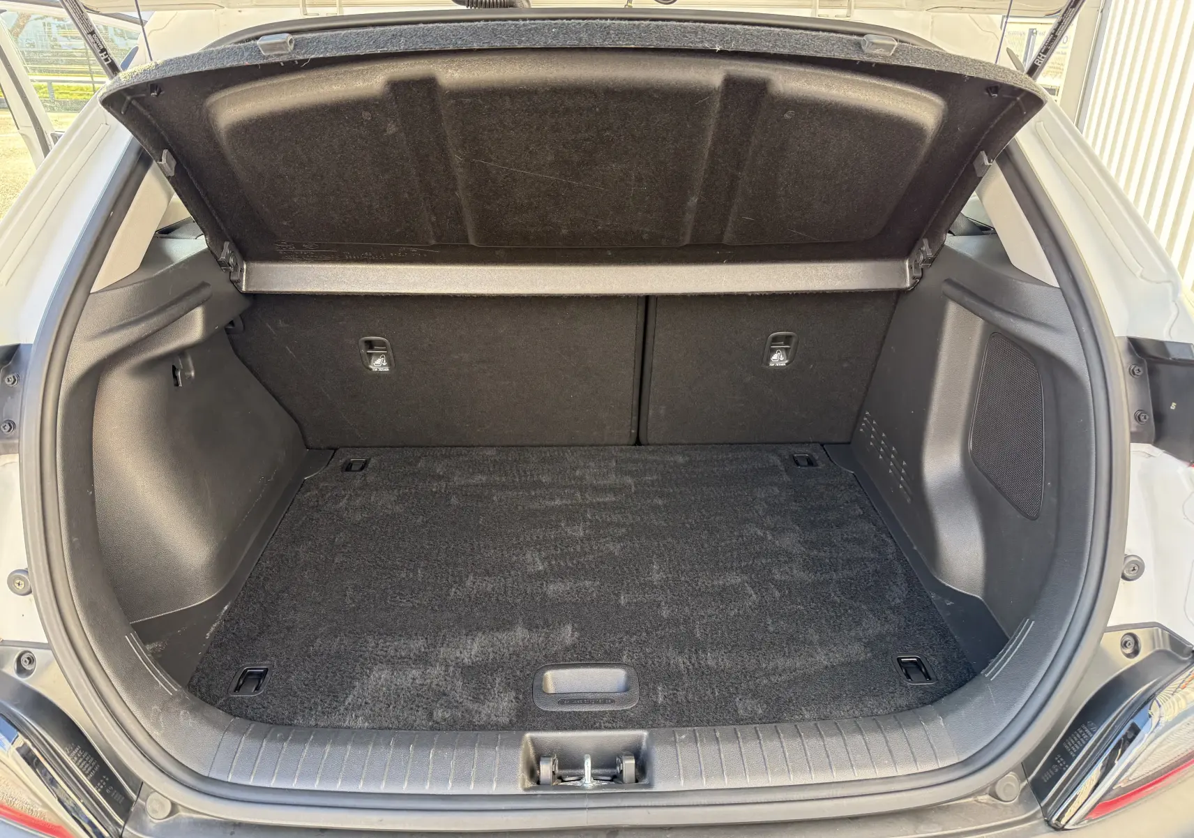 Coffre ouvert vu de l'arrière du Hyundai Kona blanc Atlas 2021, espace de chargement propre et vide.