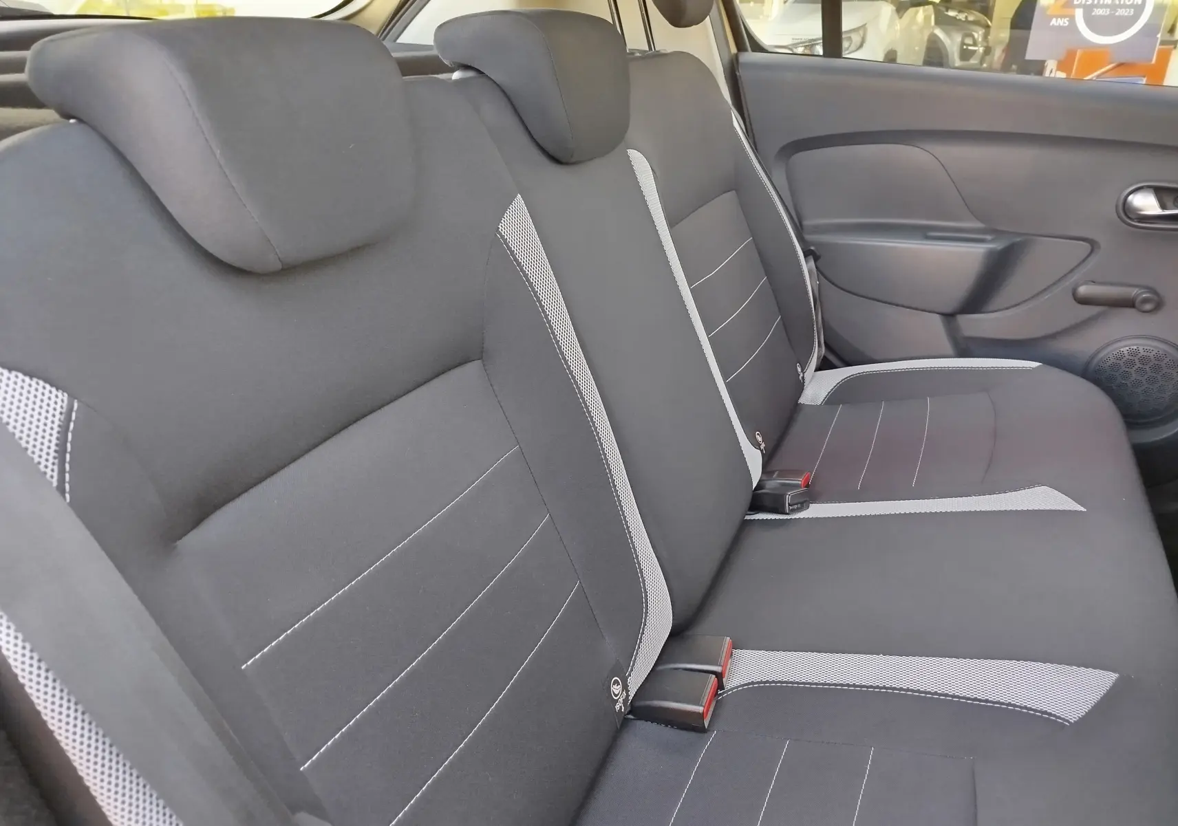 Vue latérale des sièges arrière noirs et gris en tissu de la Dacia Sandero Stepway 2020, intérieur spacieux et sobre.