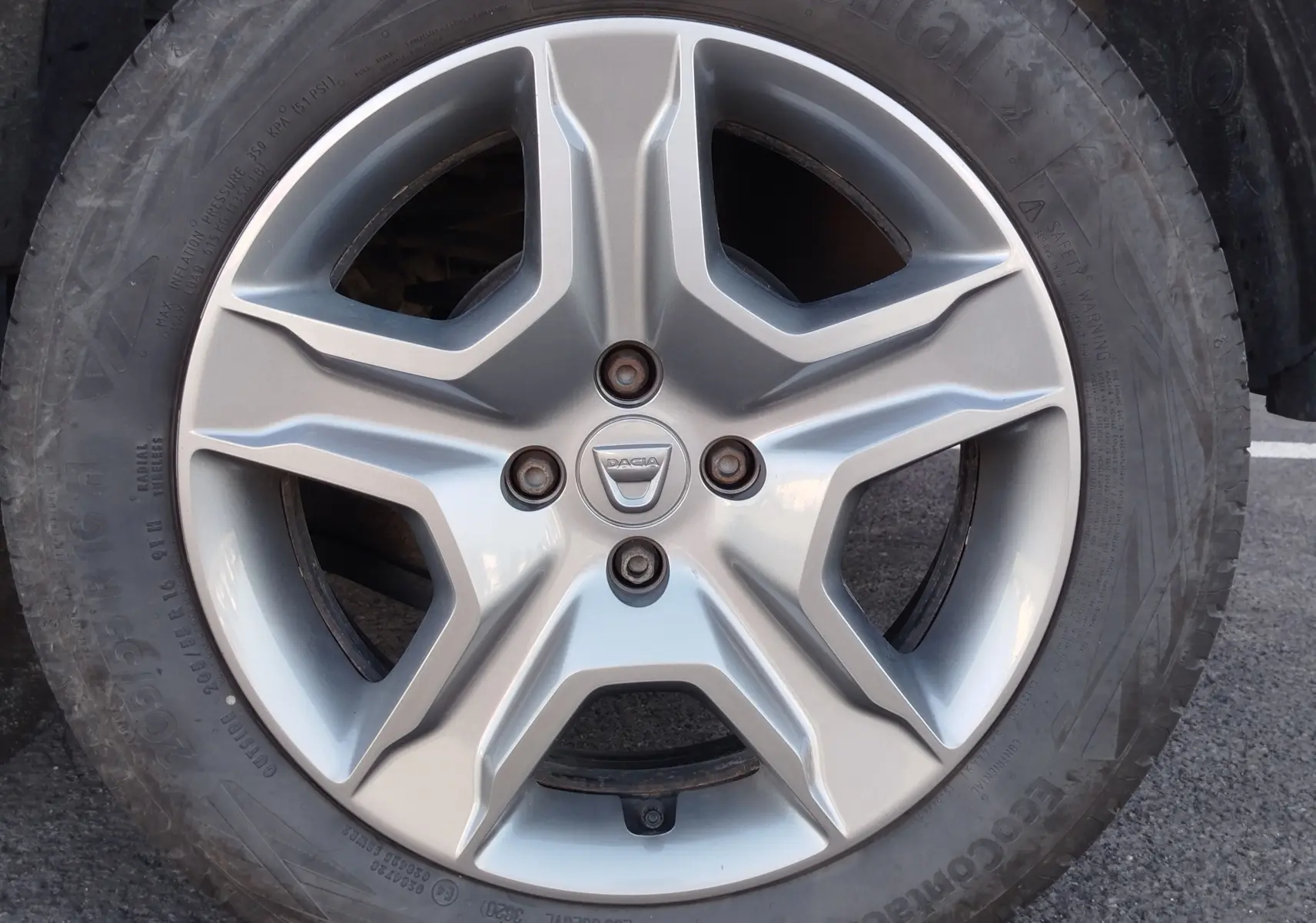 Vue de profil côté gauche d'une Dacia Sandero Stepway beige dune garée sur un sol bitumé.