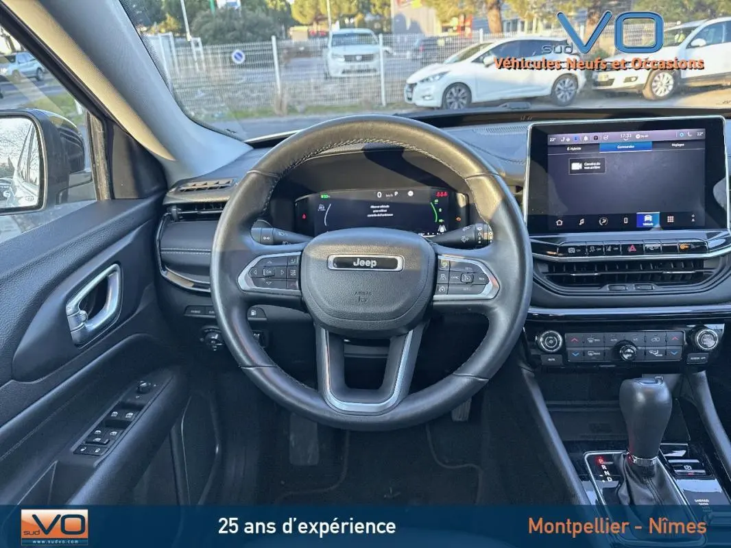 Vue intérieure centrée sur le volant cuir Jeep Compass blanc 2023 avec écran tactile et commandes au volant