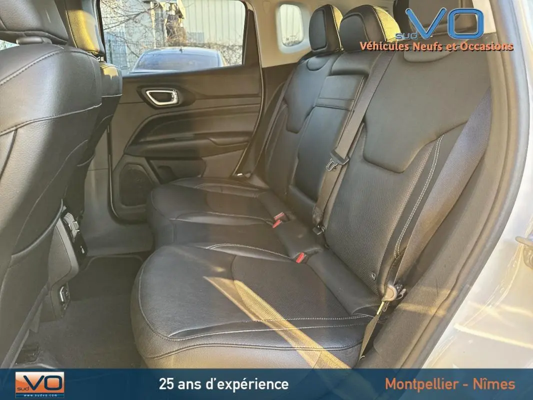 Vue intérieure des sièges arrière en cuir noir du Jeep Compass blanc 2023, avec ceinture de sécurité et porte côté droit visible.