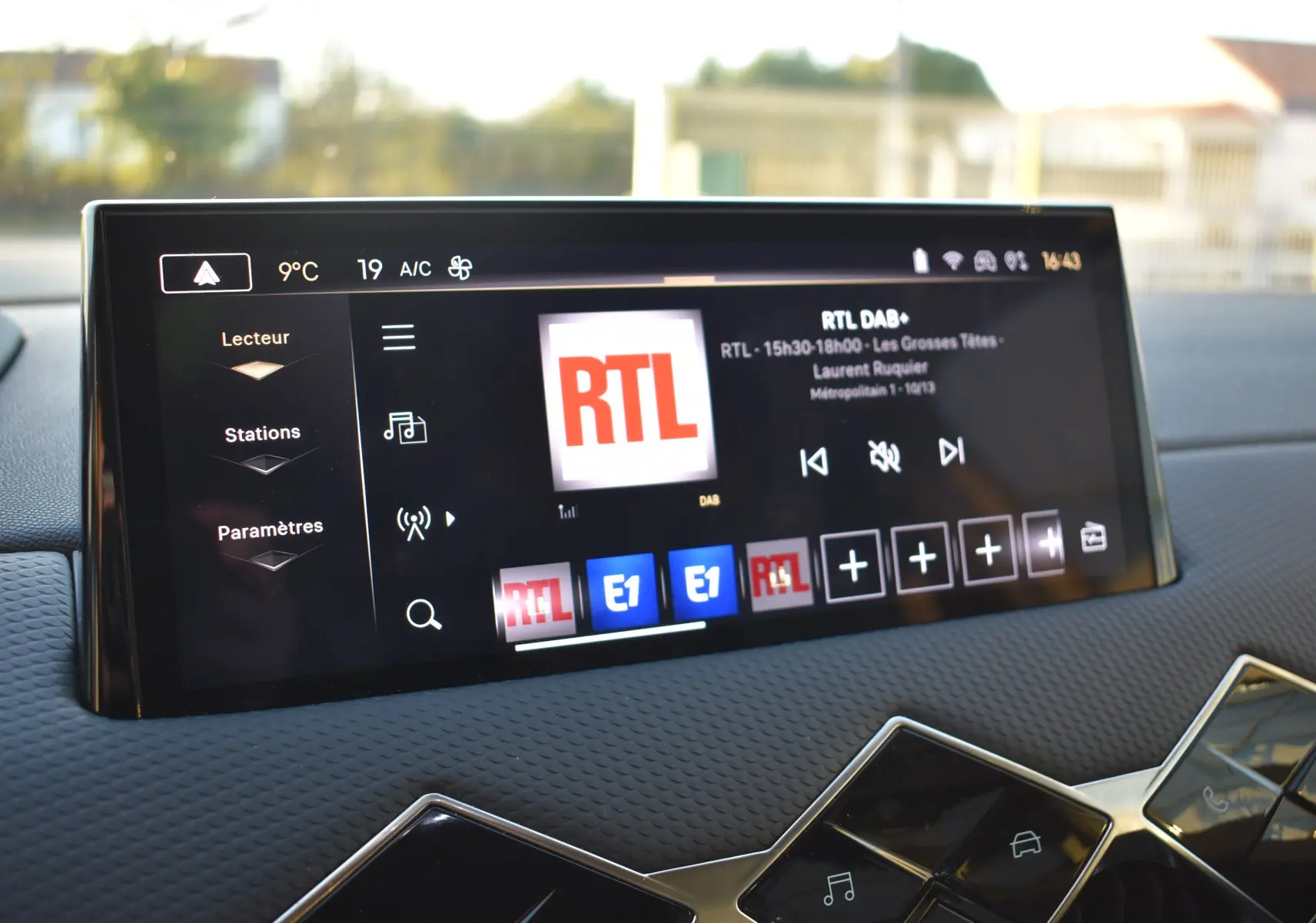 Écran tactile central du DS3 Crossback 2024 affichant la radio RTL, avec tableau de bord noir texturé en arrière-plan.