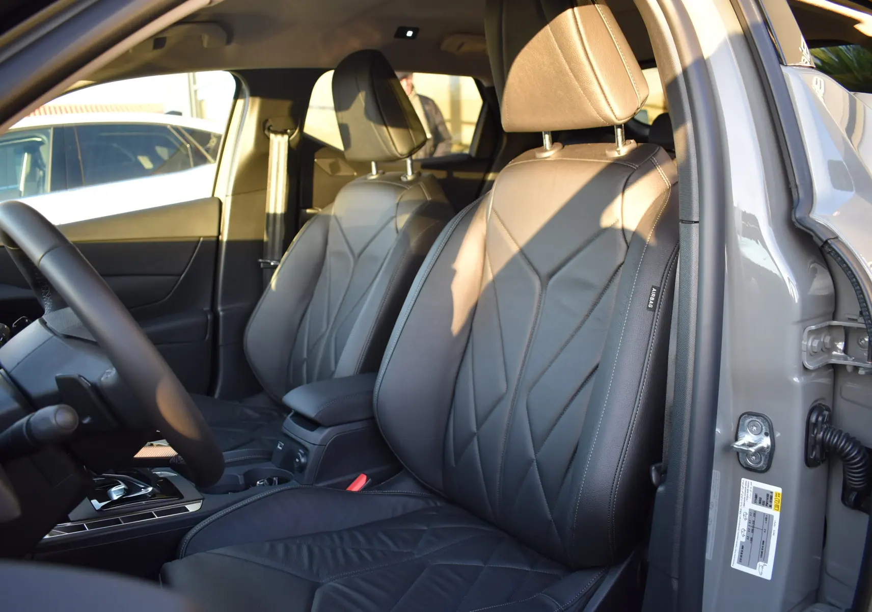 Vue intérieure côté conducteur du DS3 Crossback 2024, sièges en cuir noir avec surpiqûres et volant partiellement visible.