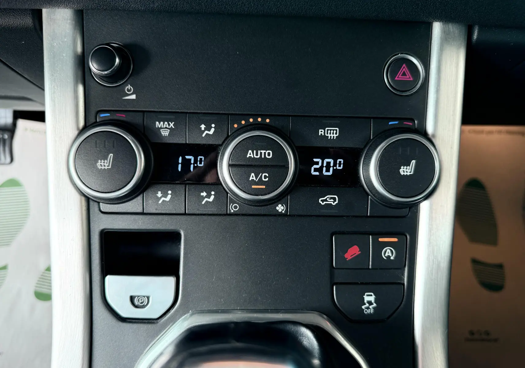 Gros plan sur la console centrale noire du Range Rover Evoque 2017, montrant les commandes de climatisation et d'assistance conduite.