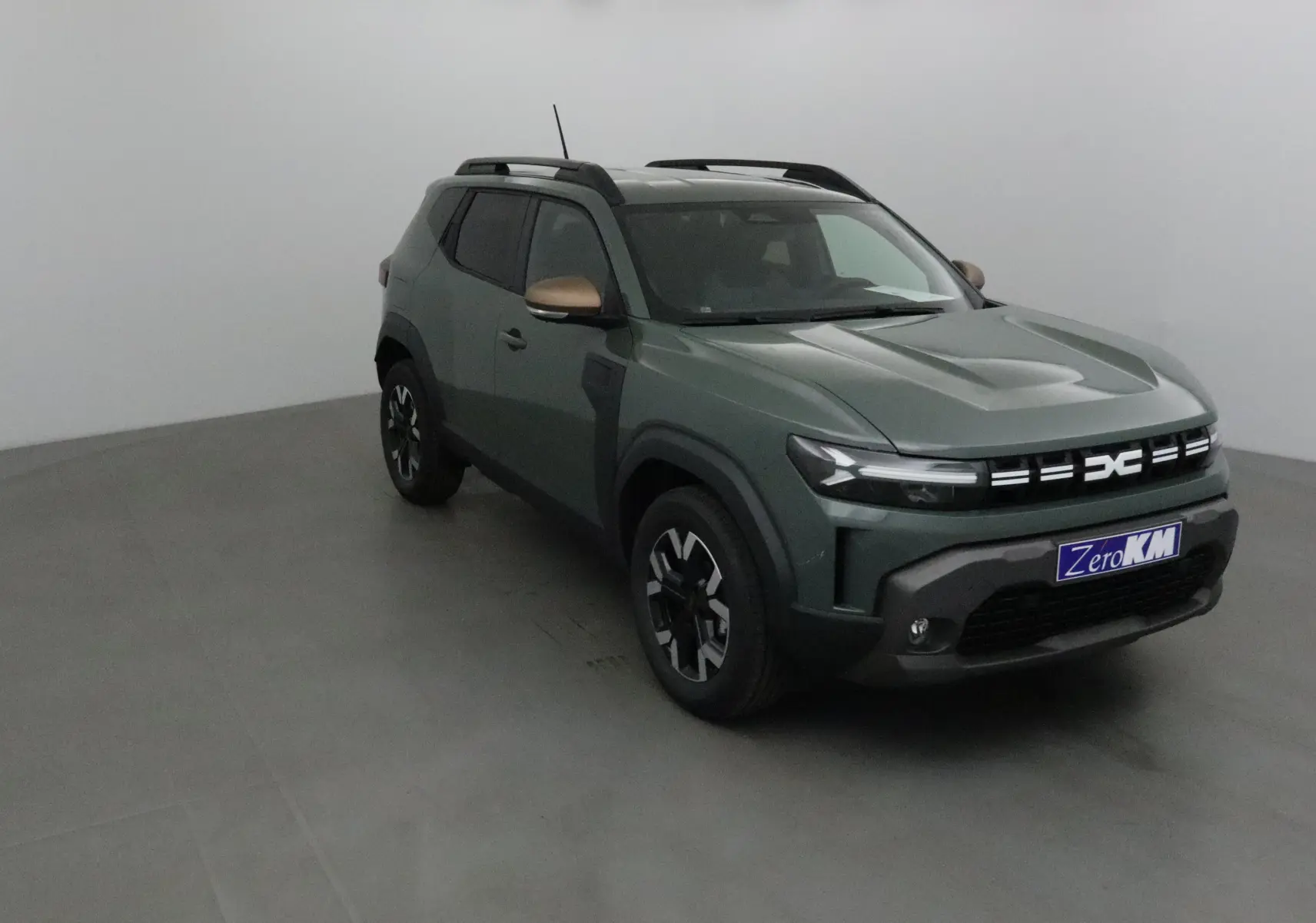 Dacia Duster 2025 kaki lichen en 3/4 avant droit avec jantes noires et coques de rétroviseur bronze.