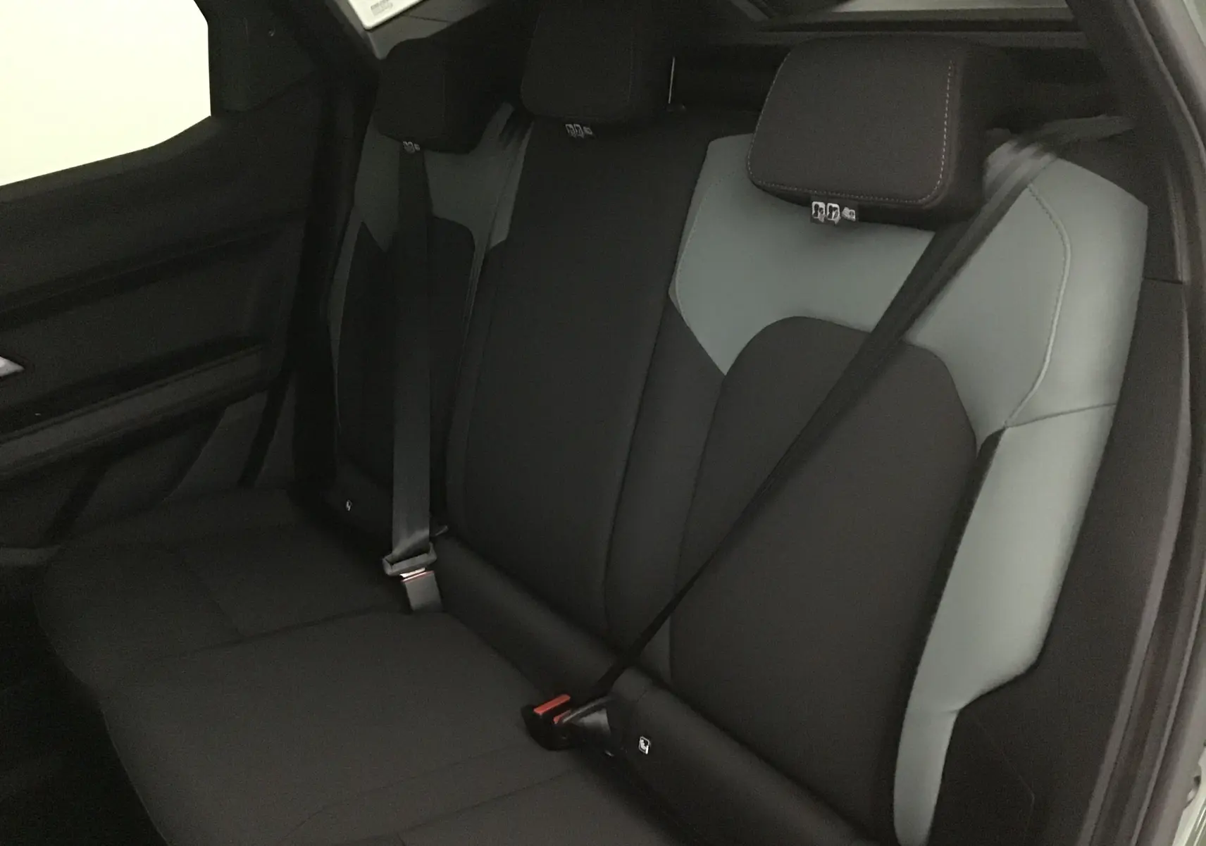 Vue intérieure arrière du Dacia Duster 2025, sièges bicolores noirs et gris avec ceinture de sécurité noire.